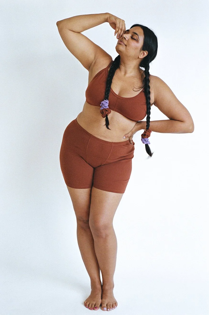 Model bends while wearing Pansy Stretch Shorts in the color Wine.