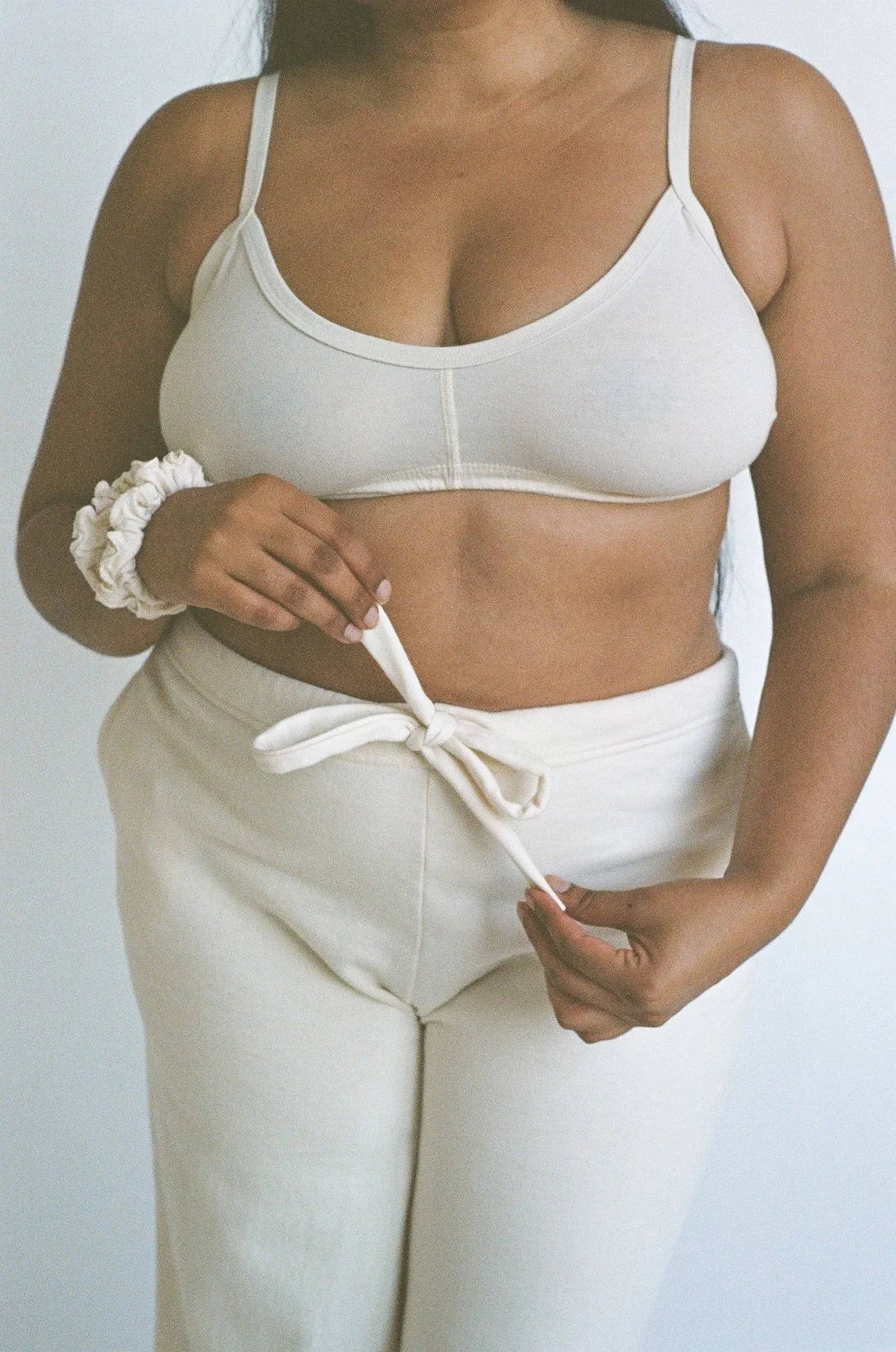 A model adjusts the drawstring of her Pansy organic cotton fleece pants in the color Natural.