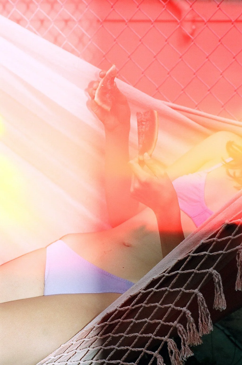 A model in lilac underwear holds watermelon slices while reclining in a hammock, with orange and yellow light across the scene.
