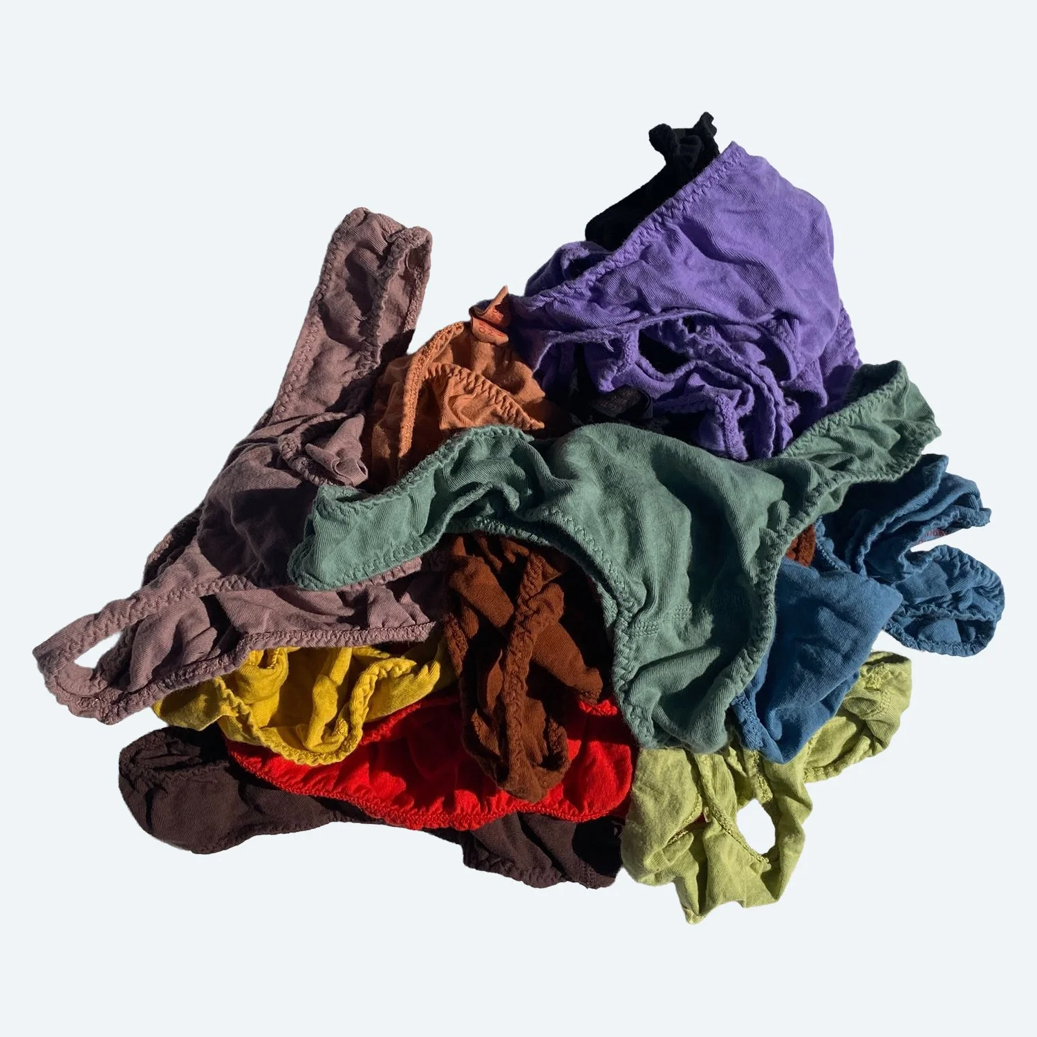 Flat lay of Pansy sample thongs in assorted colors on a pale blue-gray background.