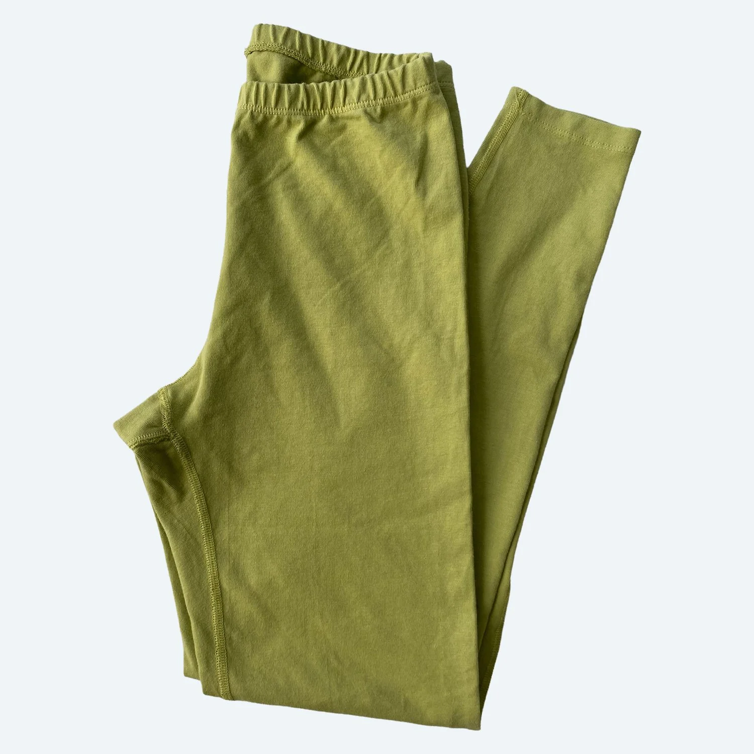 Flat lay of Pansy surprise leggings in avocado green on a pale blue-gray background.