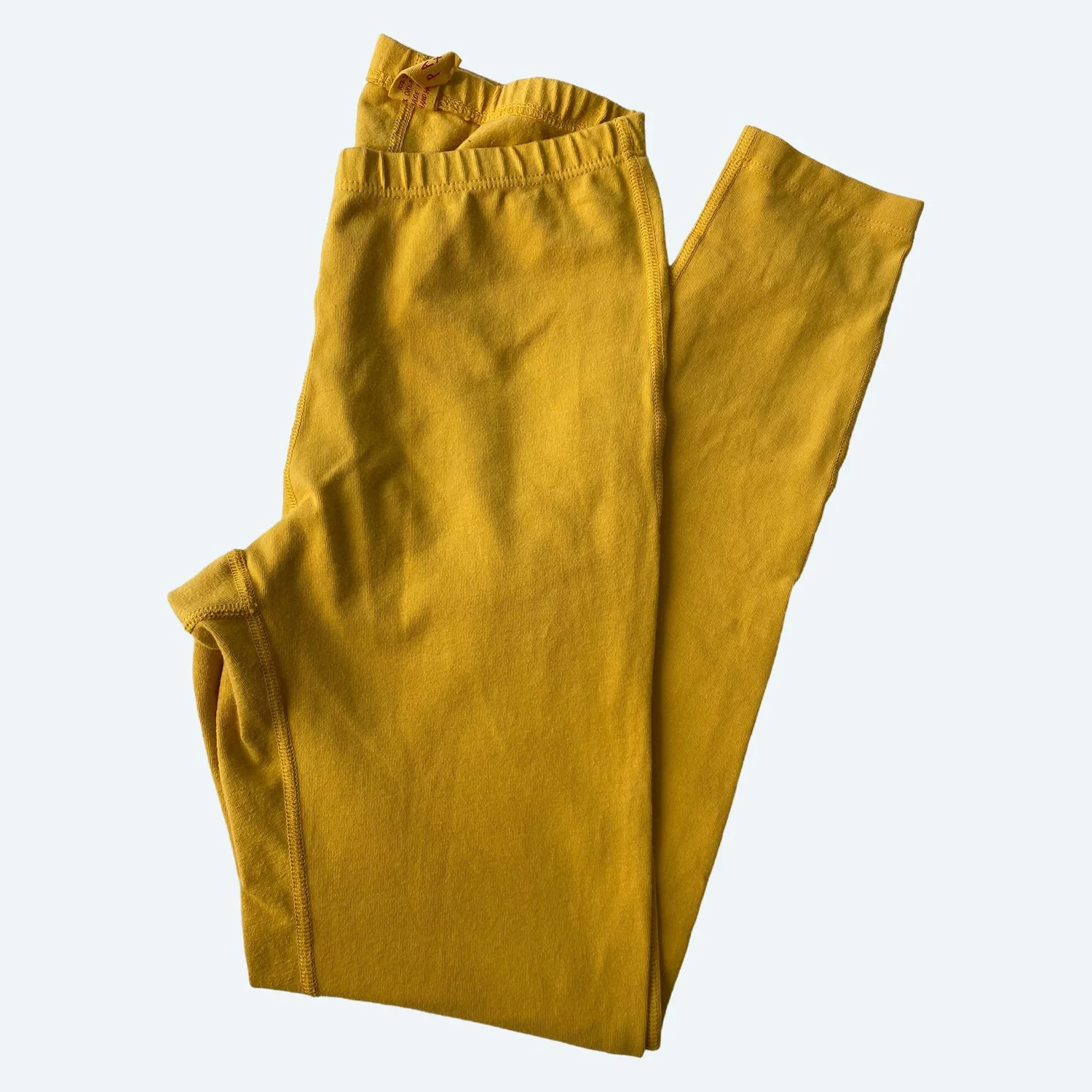 Flat lay of Pansy leggings in sunflower yellow on a pale blue-gray background.