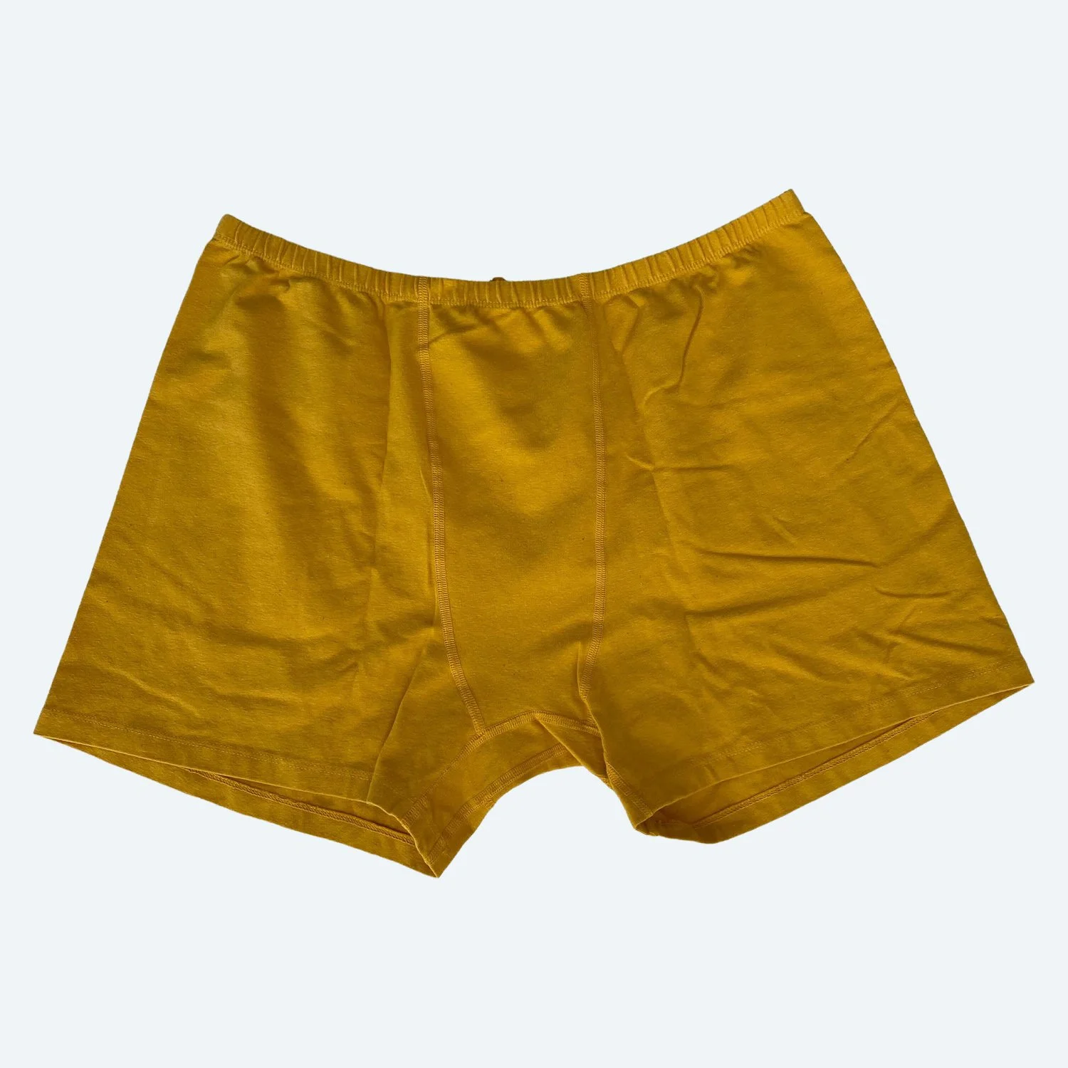 Flat lay of Pansy stretch shorts in sunflower yellow on a pale blue-gray background.