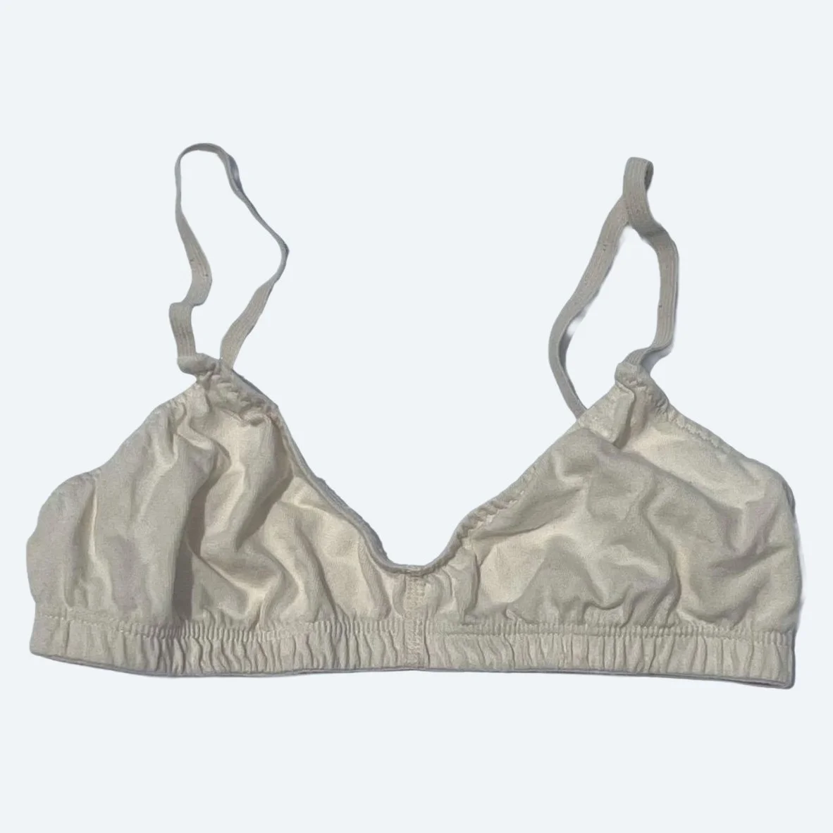 Flat lay of Pansy original bra in natural on a pale blue-gray background.