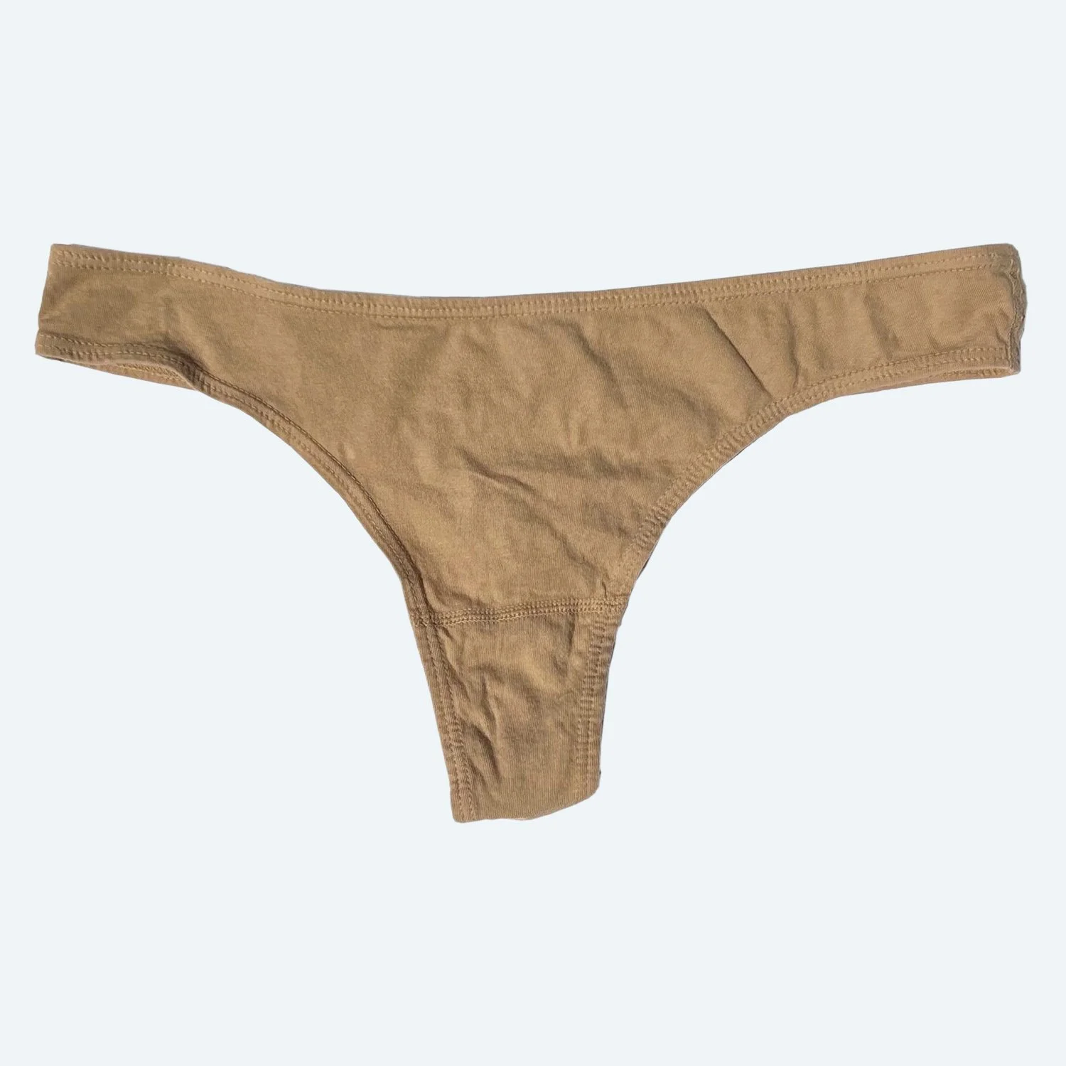 Flat lay of Pansy thong in sand on a pale blue-gray background.