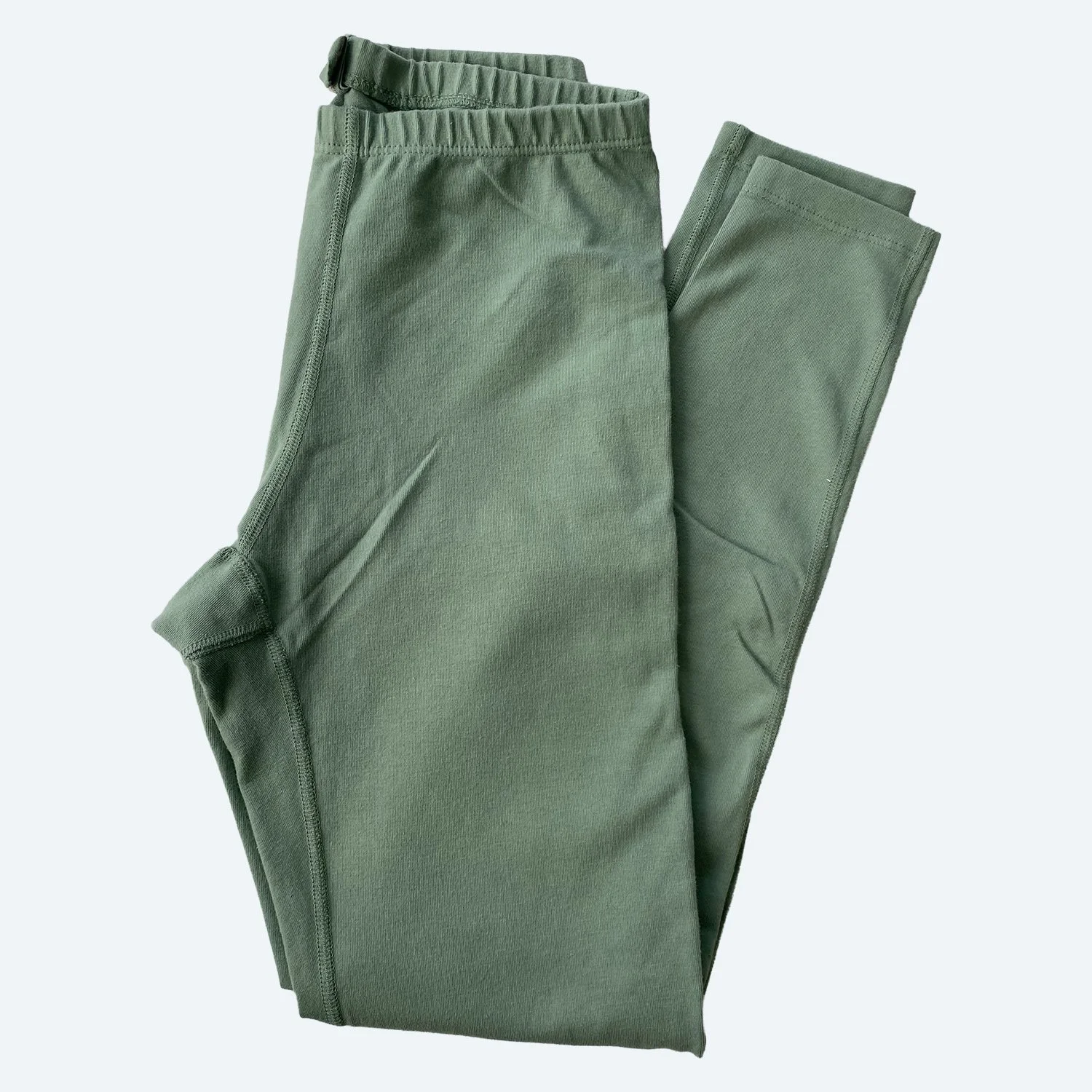 Flat lay of Pansy leggings in mermaid green on a pale blue-gray background.