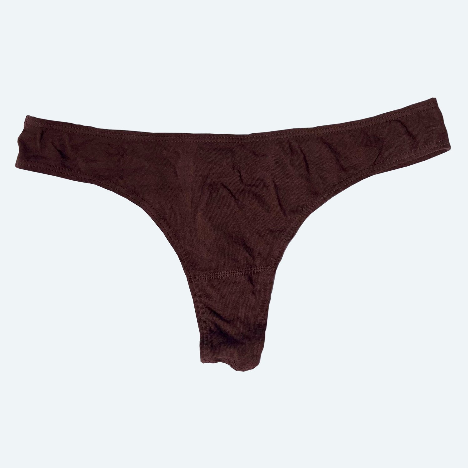 Flat lay of Pansy thong in cocoa brown on a pale blue-gray background.