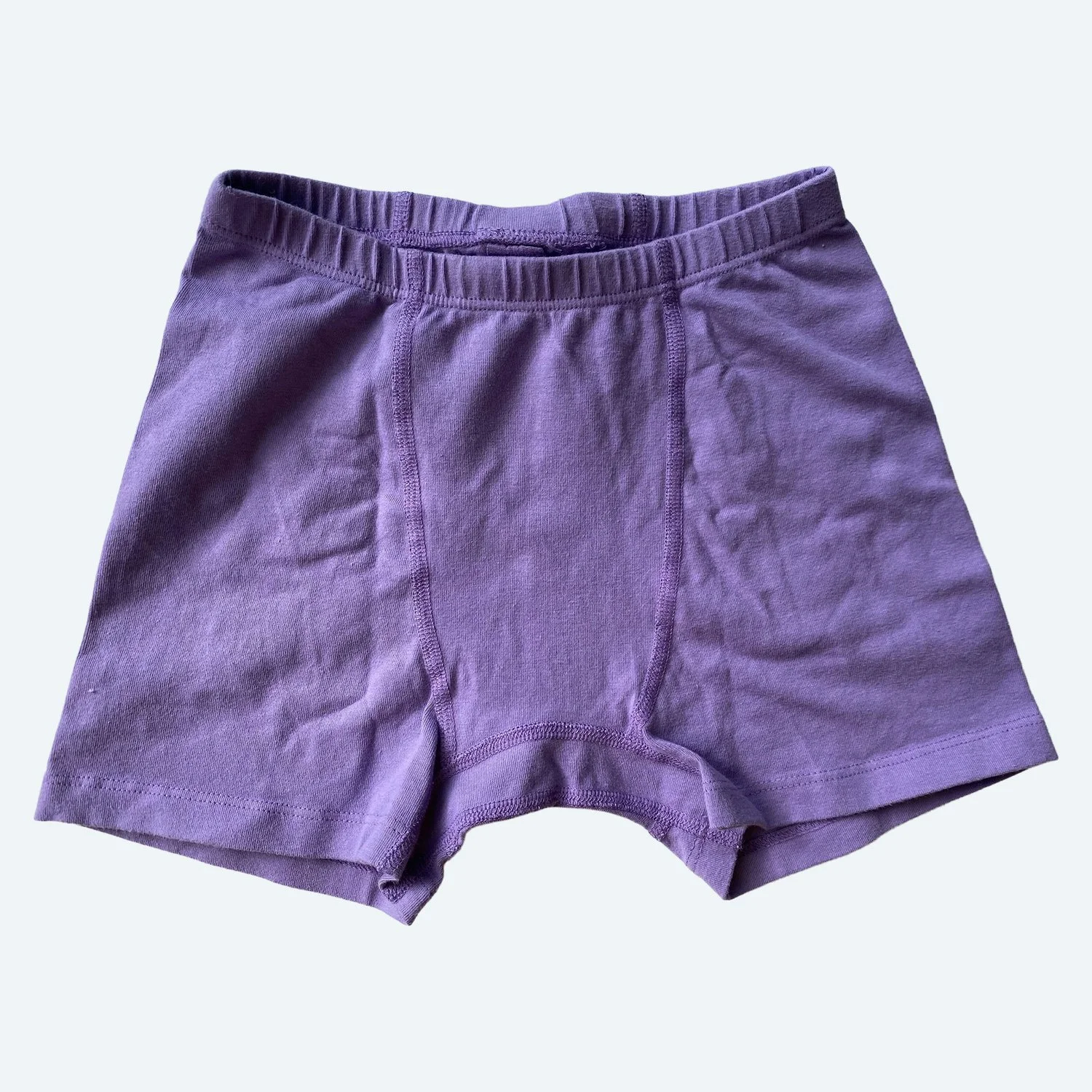 Flat lay of Pansy xxs stretch shorts in lilac purple on a pale blue-gray background.
