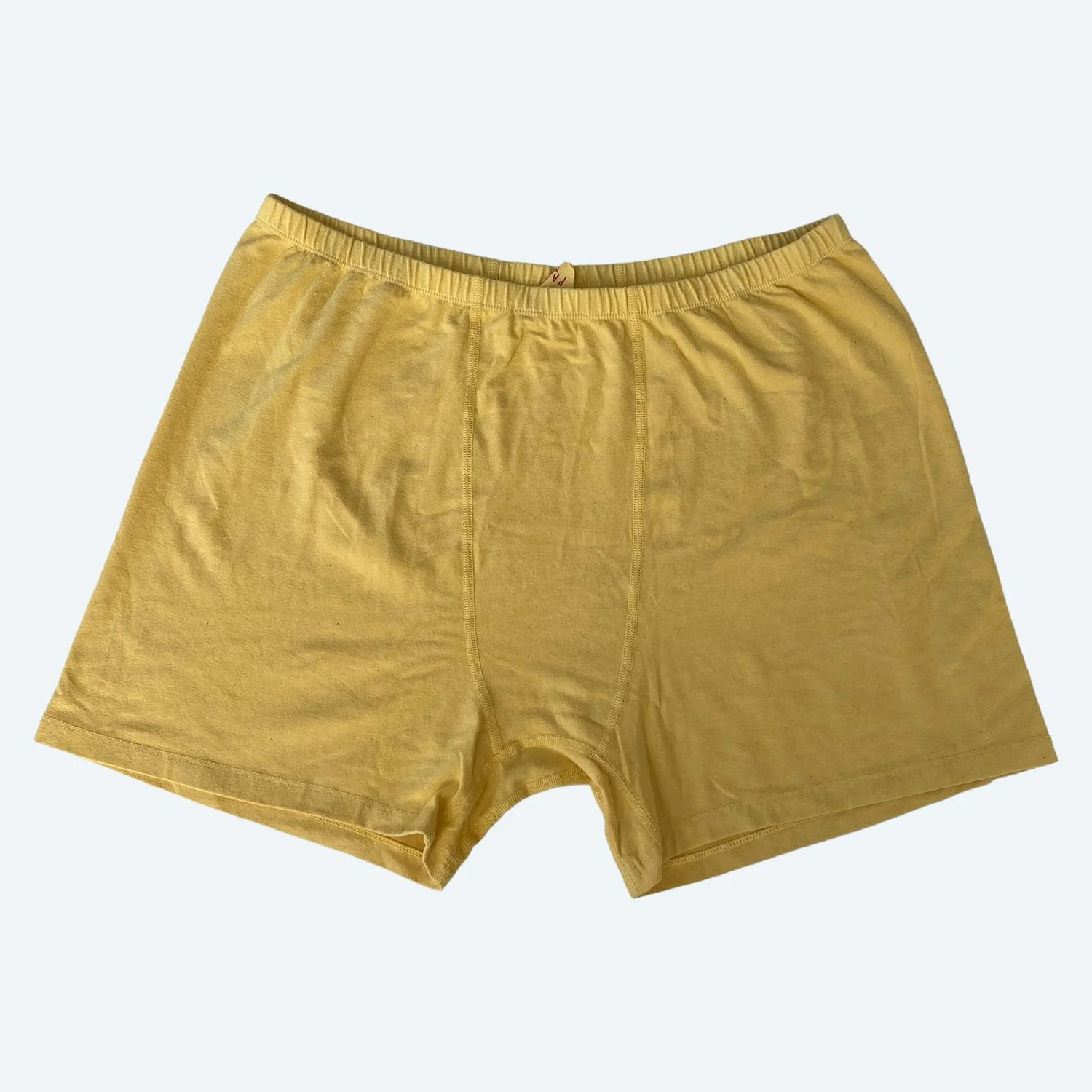 Flat lay of Pansy stretch shorts in butter yellow on a pale blue-gray background.