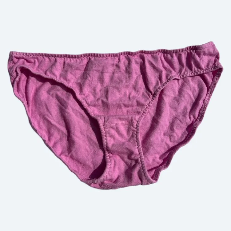 Flat lay of Pansy low rise underwear in sherbet pink on a pale blue-gray background.