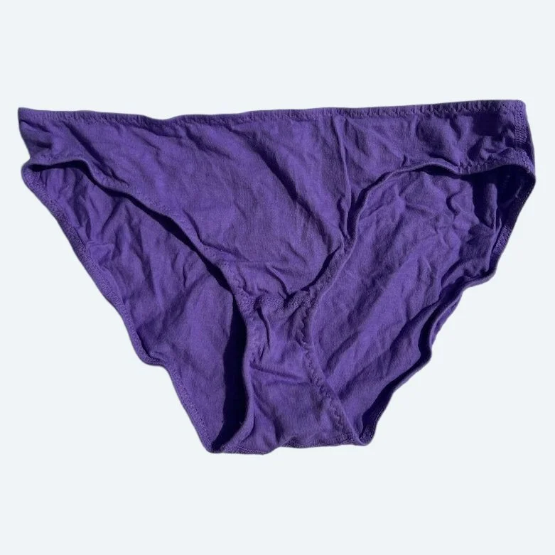 Flat lay of Pansy low rise underwear in lilac purple on a pale blue-gray background.