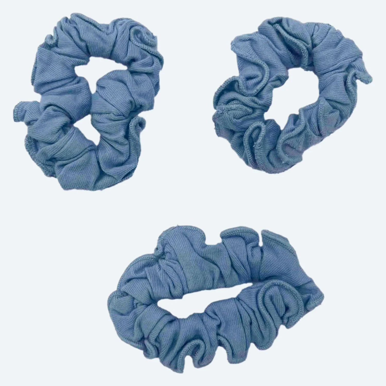 Three Pansy organic cotton scrunchies in Sky blue, laid flat.