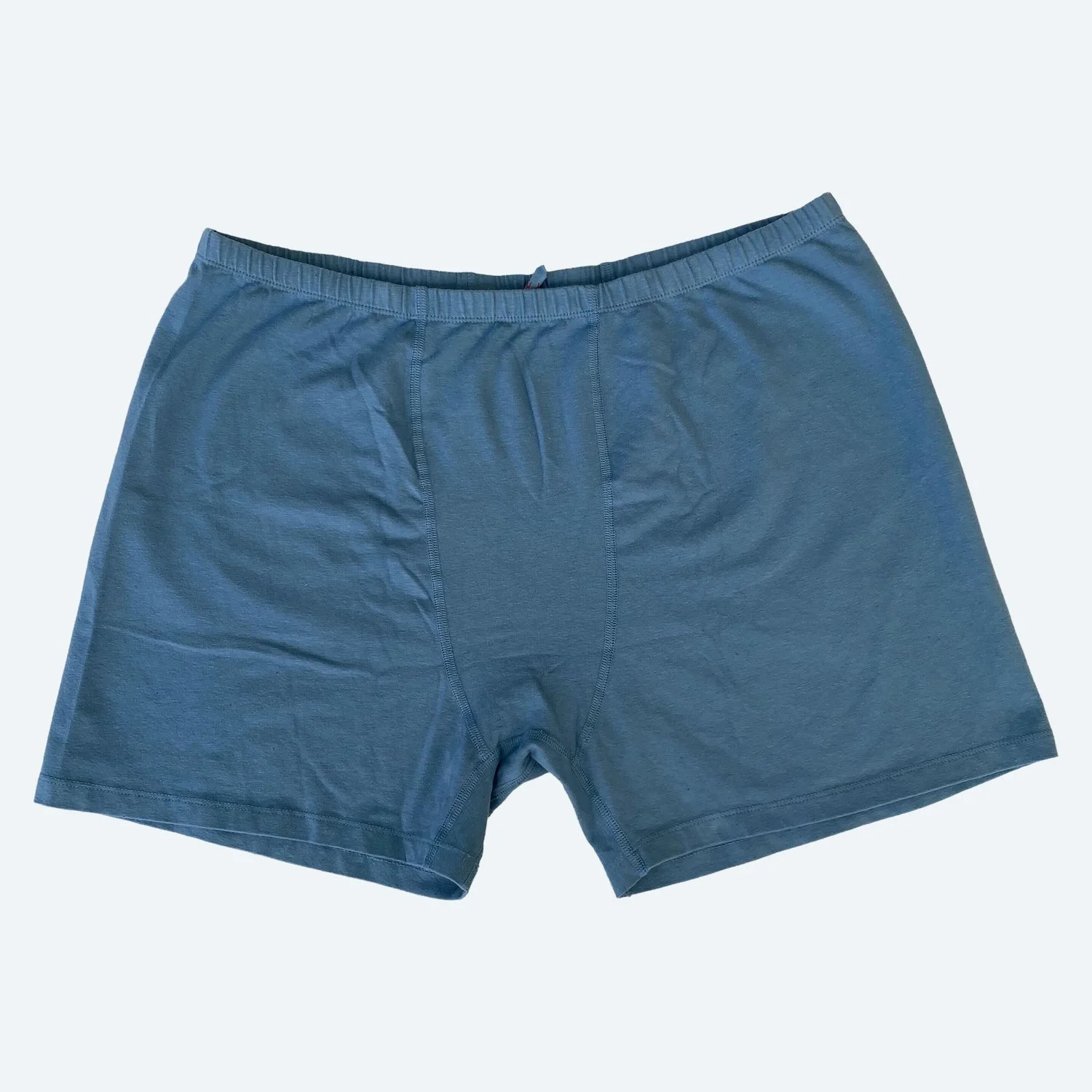 Flat lay of Pansy stretch shorts in azul blue on a pale blue-gray background.