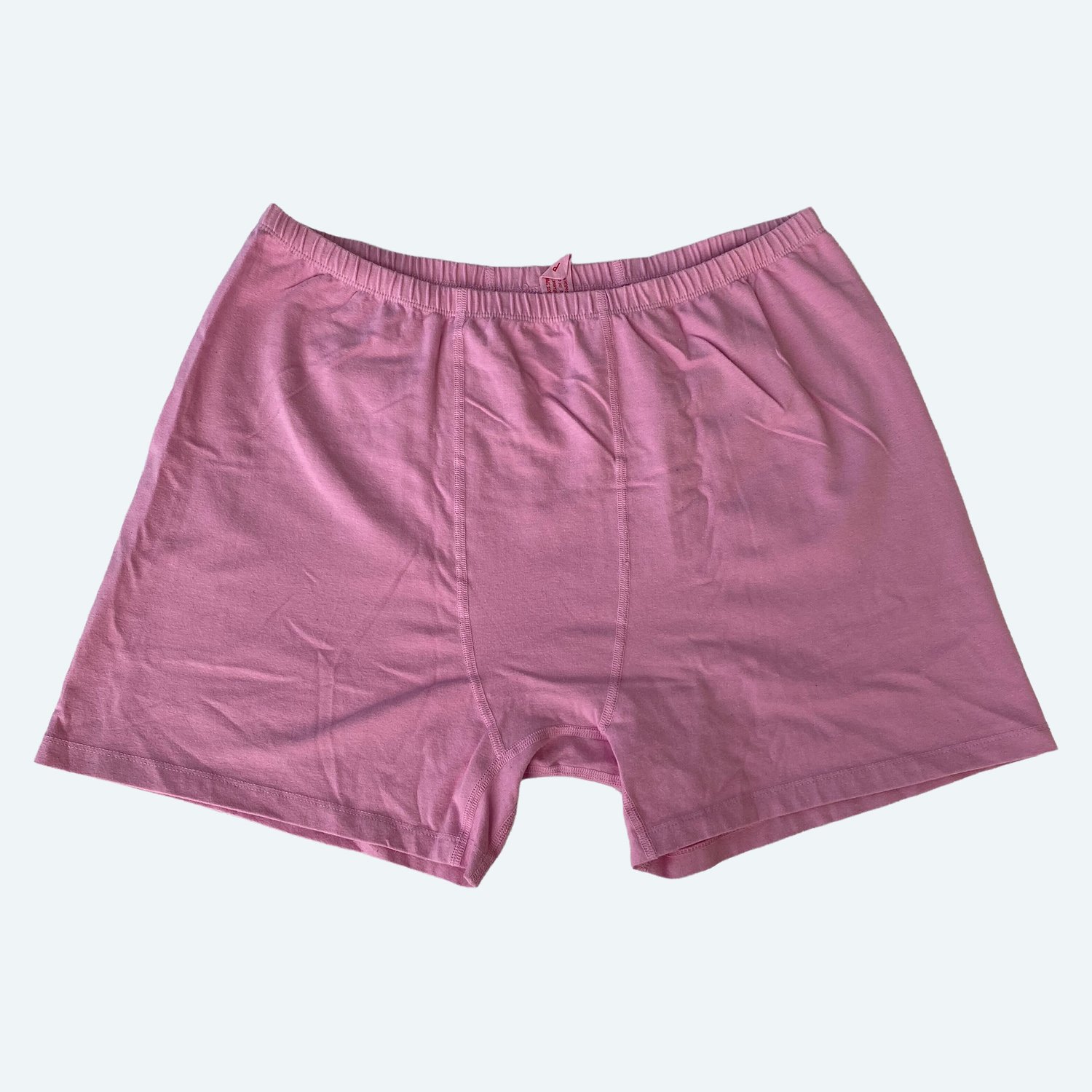 Flat lay of Pansy stretch shorts in sherbet pink on a pale blue-gray background.