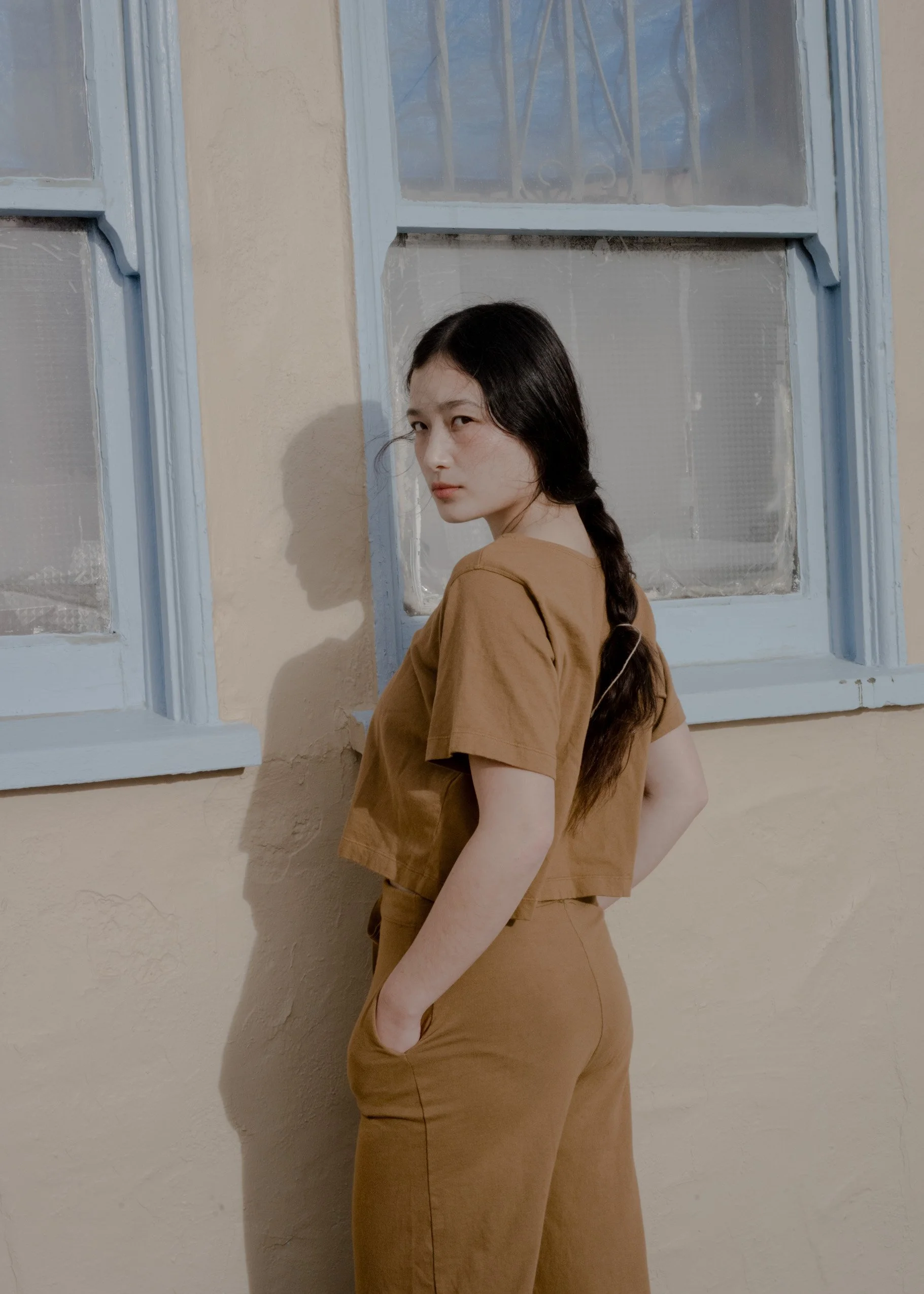 Three-quarter back view of a model wearing Pansy organic cotton Drawstring Pants in Almond with a matching Crop Top.