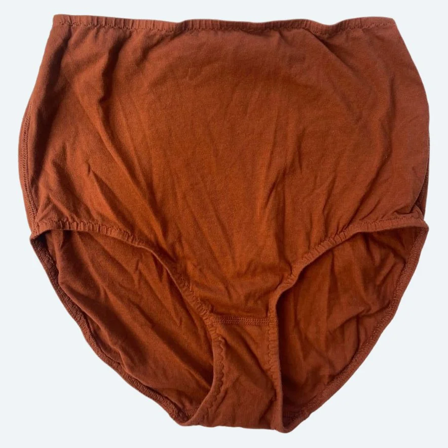 Flat lay of Pansy light xtra high rise underwear in rust on a pale blue-gray background.