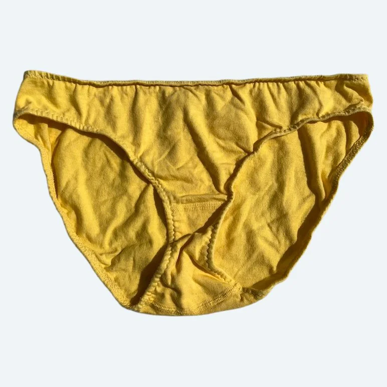 Flat lay of Pansy low rise underwear in butter yellow on a pale blue-gray background.