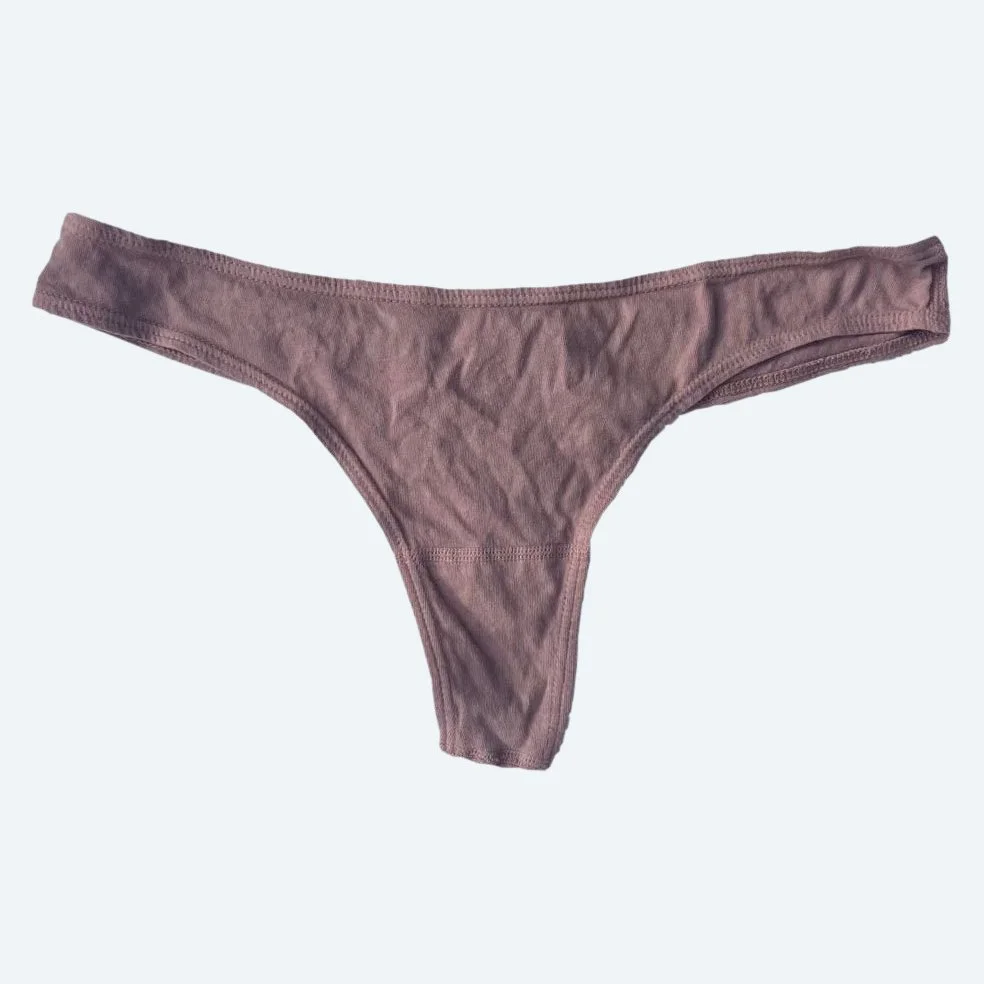 Flat lay of Pansy thong in mauve on a pale blue-gray background.