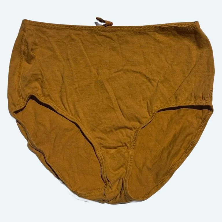 Flat lay of Pansy short xtra high rise underwear in gold on a pale blue-gray background.