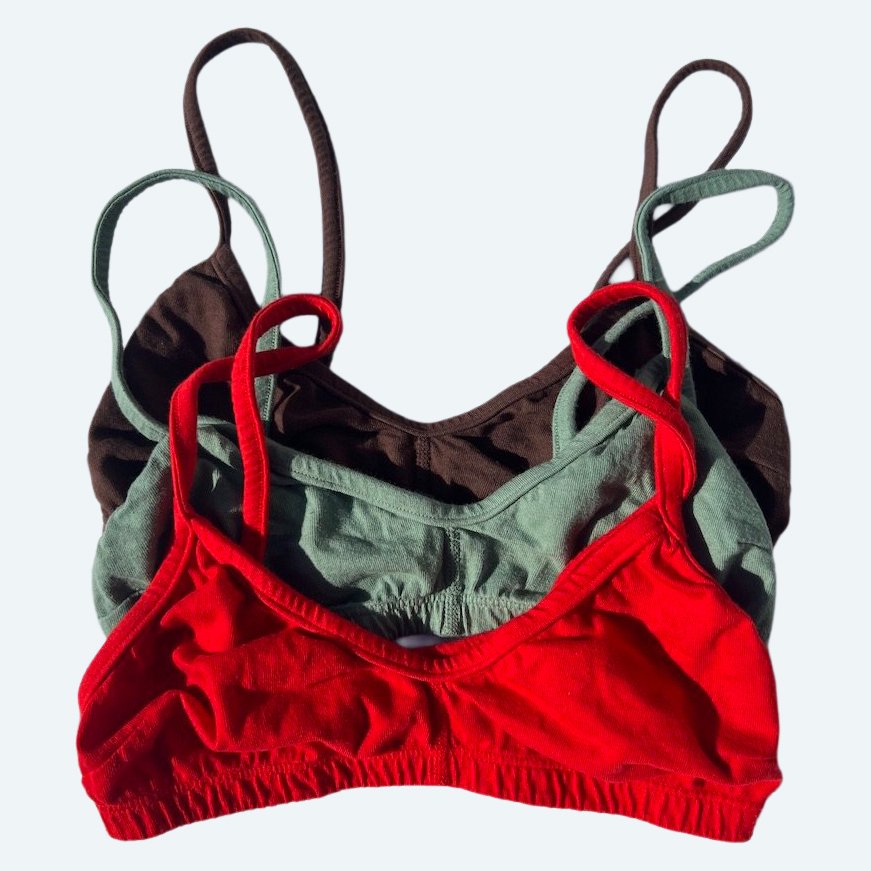 Flat lay of Pansy almost smile bra in assorted colors on a pale blue-gray background.