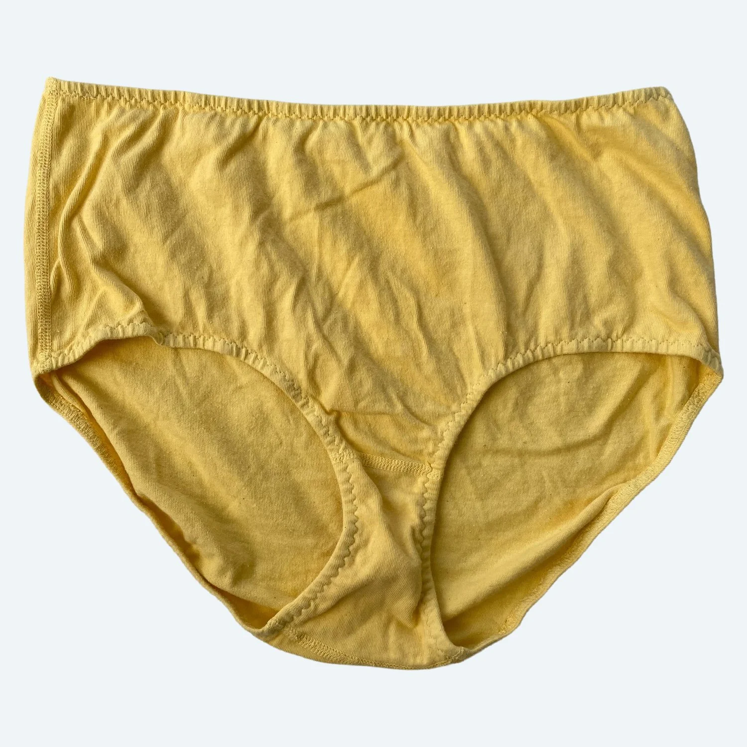 Flat lay of Pansy high rise underwear in butter yellow on a pale blue-gray background.