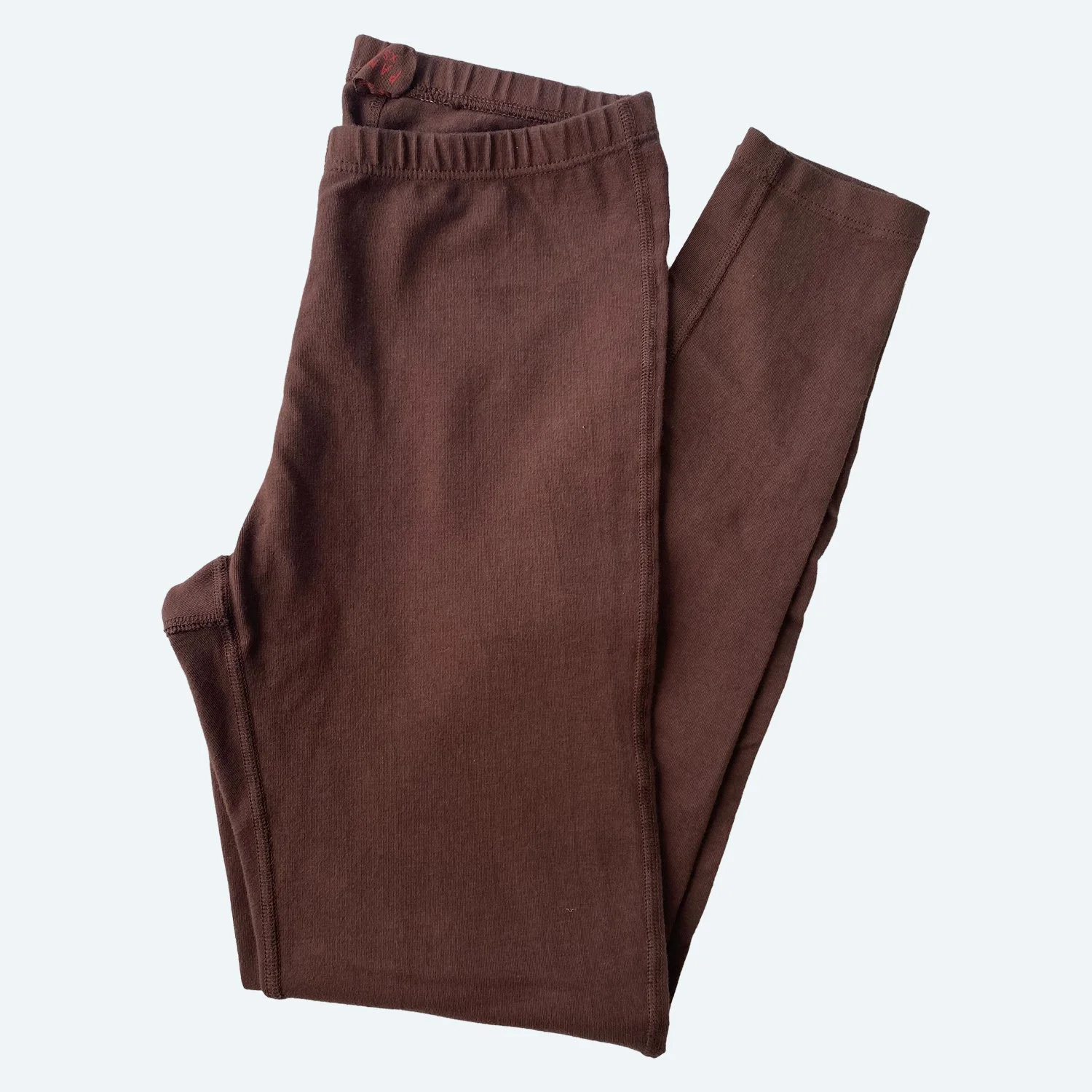 Flat lay of Pansy leggings in cocoa brown on a pale blue-gray background.