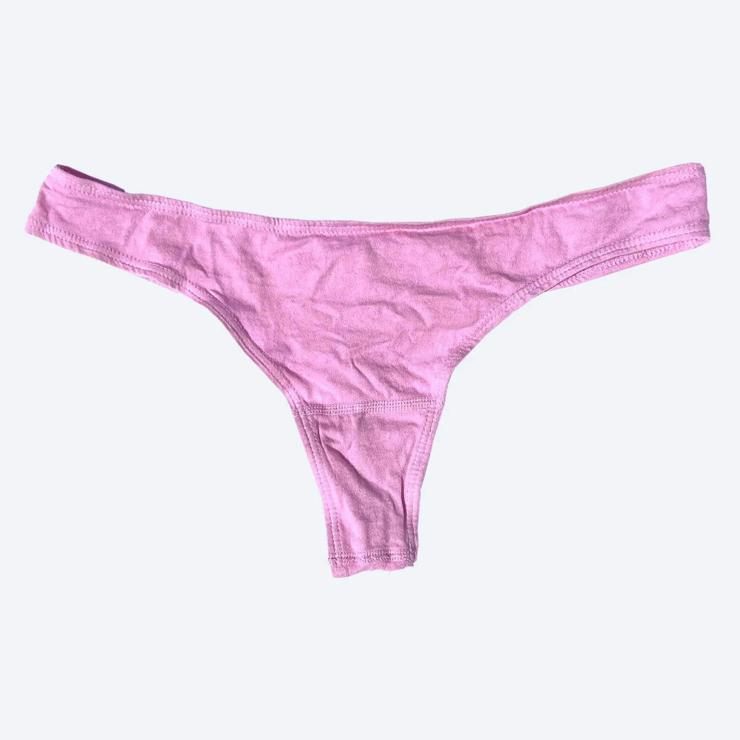 Flat lay of Pansy thong in sherbet pink on a pale blue-gray background.