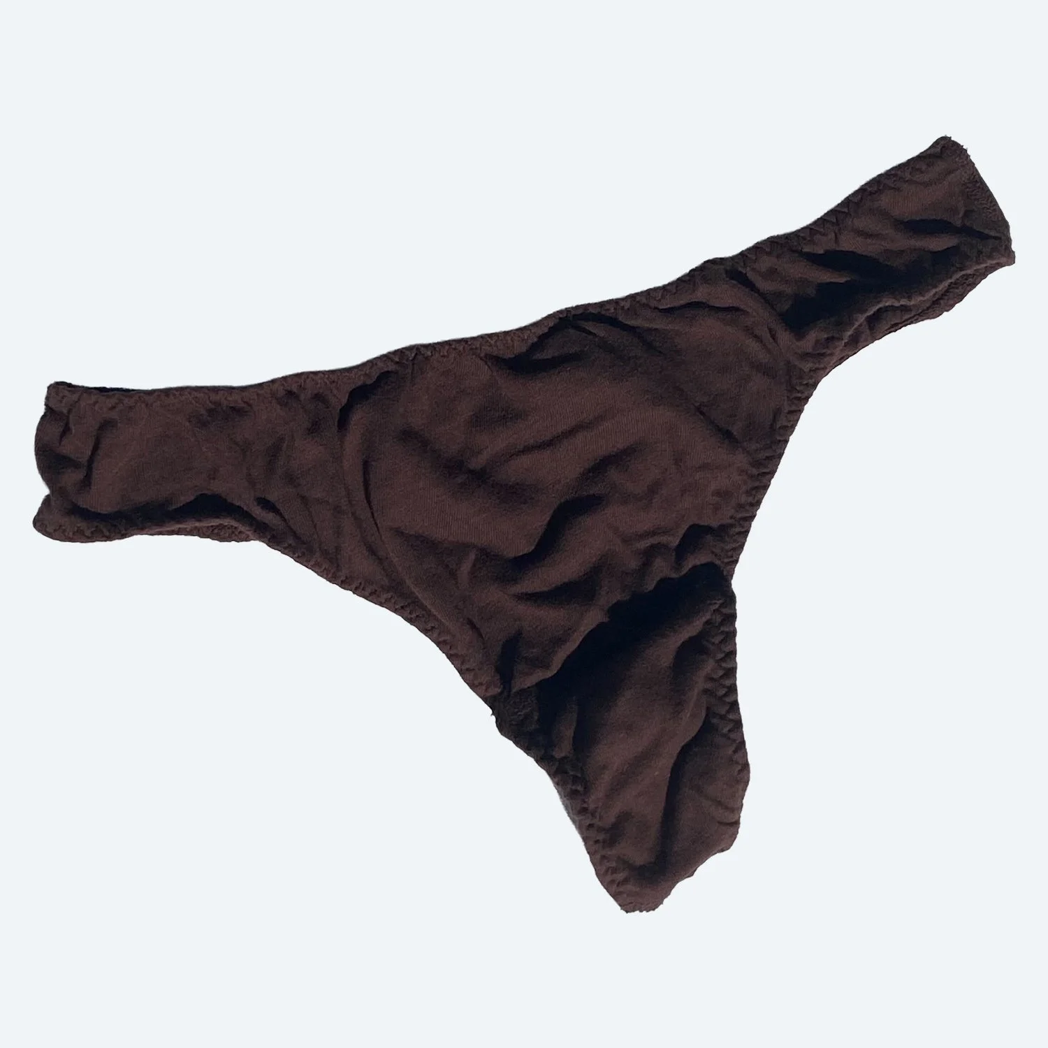 Flat lay of Pansy sample thong in cocoa brown on a pale blue-gray background.