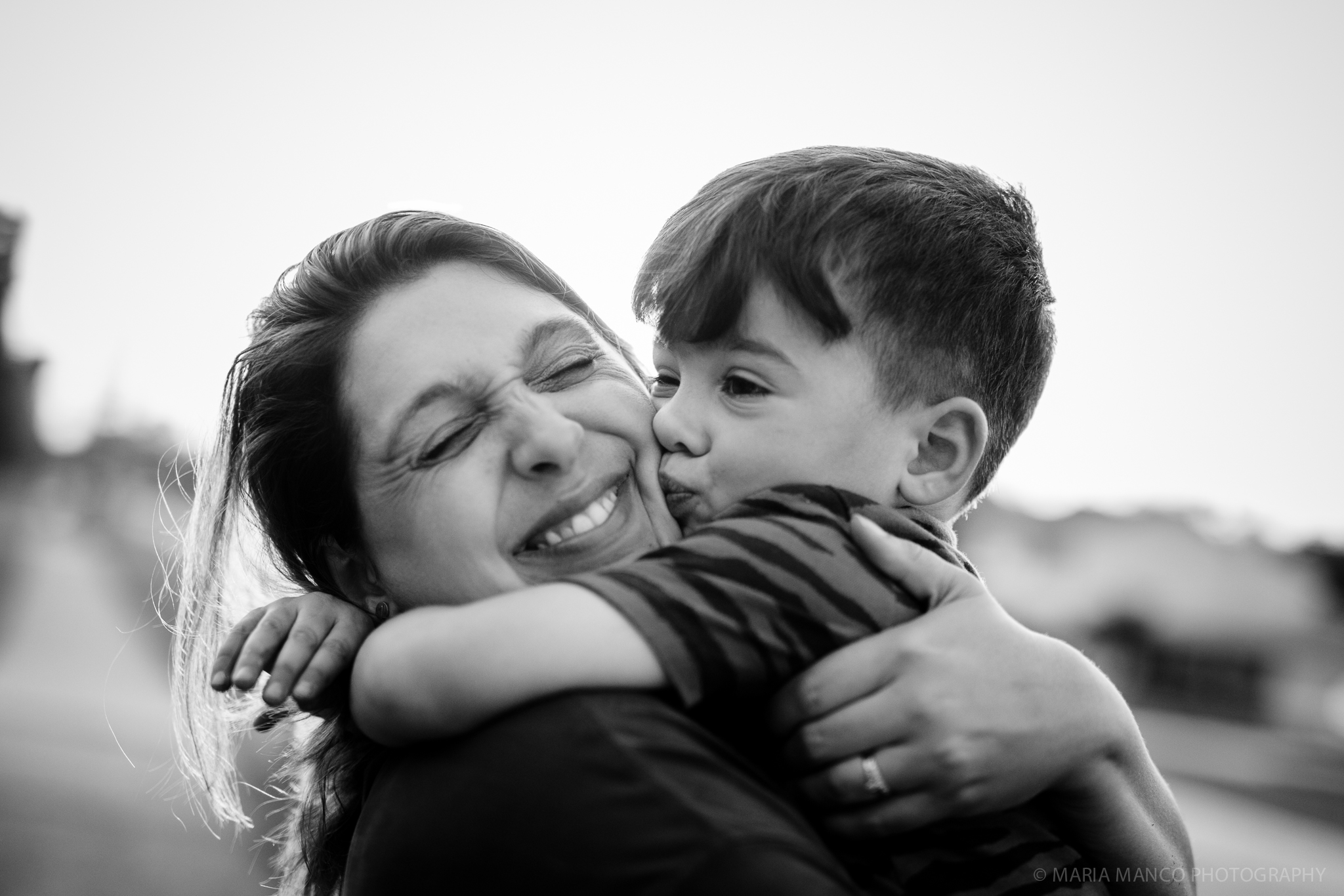 ©MariaManco _ Boy gives smiling mom a hug and kiss