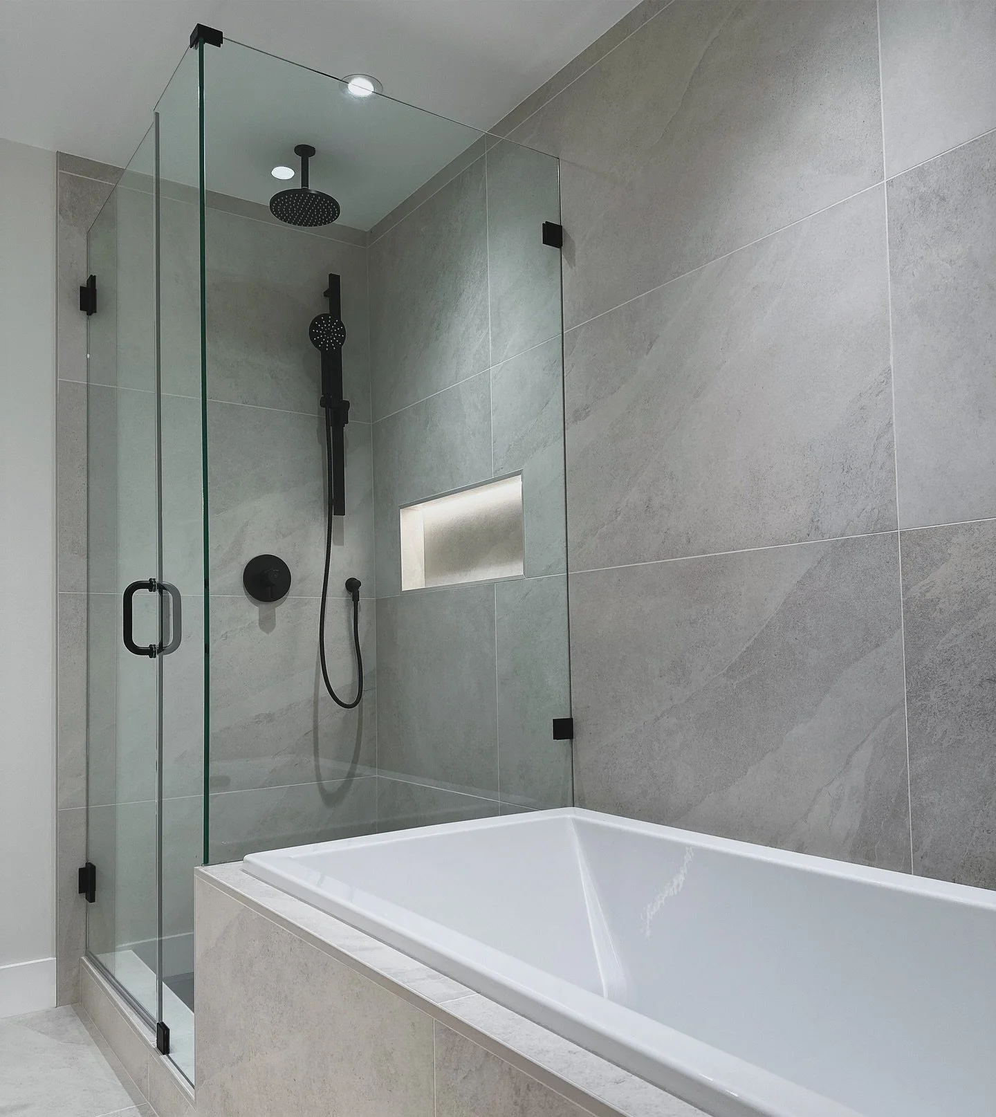 Here are some updated pictures of our modern Burke Mountain en suite renovation! Featuring sleek 24x48 tiles on both the walls and floors, this space is the perfect blend of style and function. Niche and under-cabinet lighting create a soothing ambia