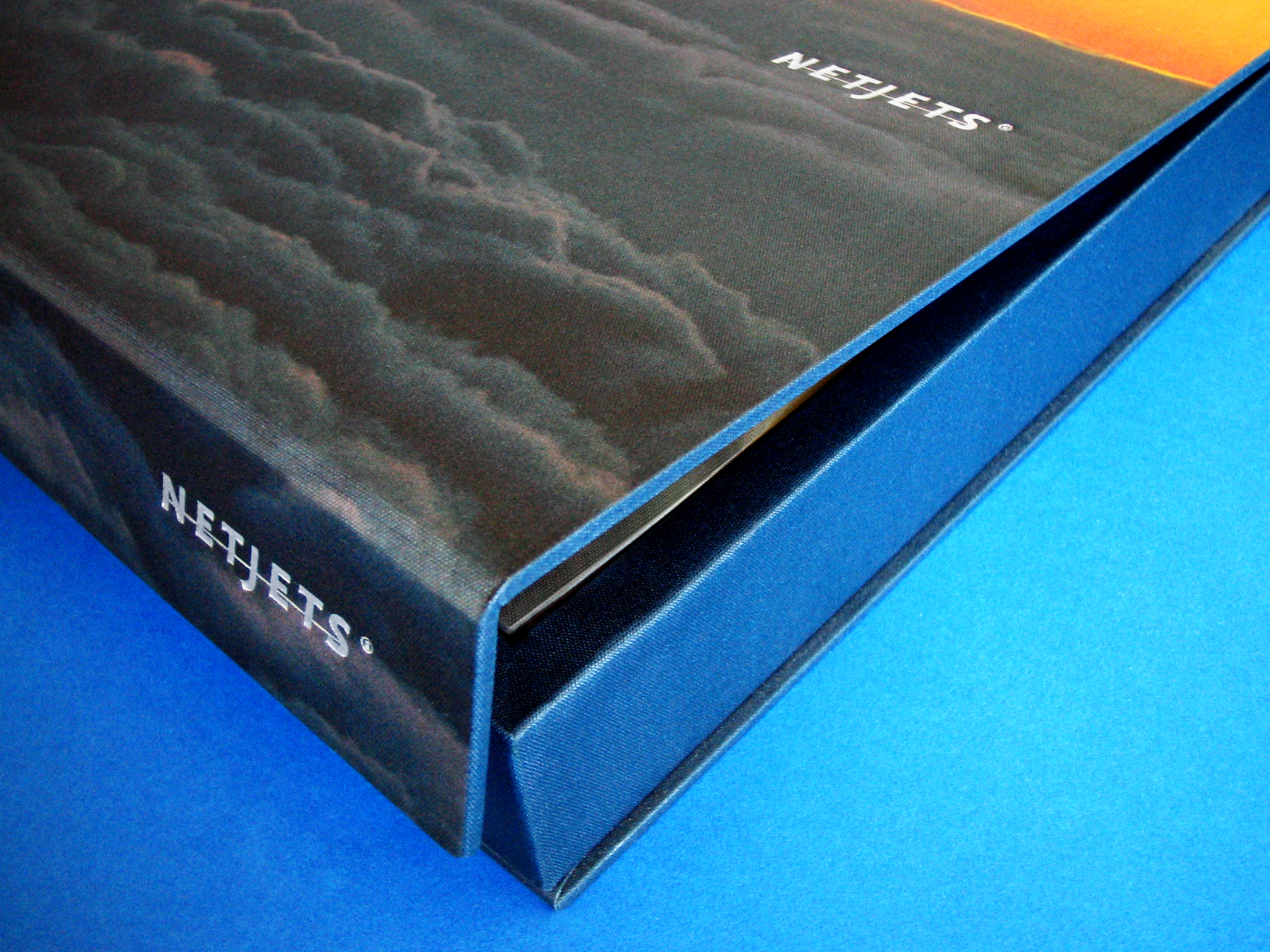 NETJETS — Wrapped silk box’s “Welcome Kit”. Nested in a coffee table book illustrating the brand’s history and fleet with multi tabbed corporate folder.
