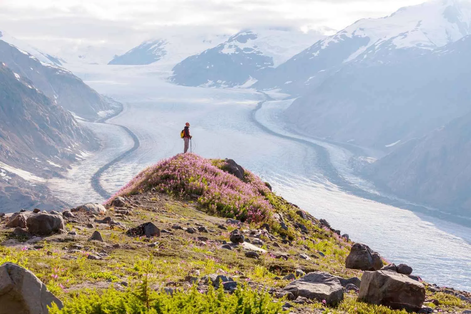 Hiker standing above a glacier on an active vacation in Alaska.