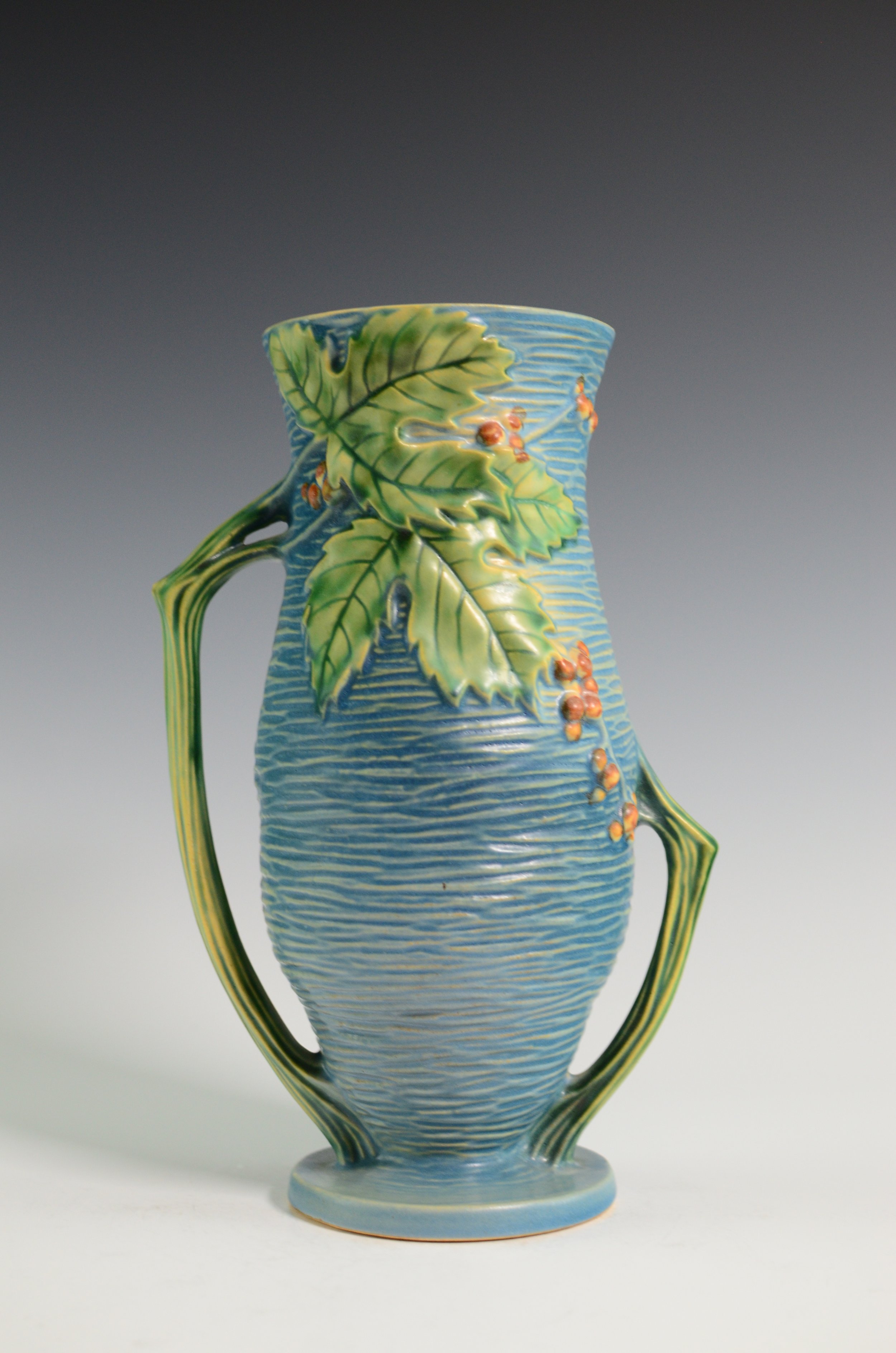 Roseville Pottery Company (1890-1954). Bushberry Vase in Blue with Leaves and Berries