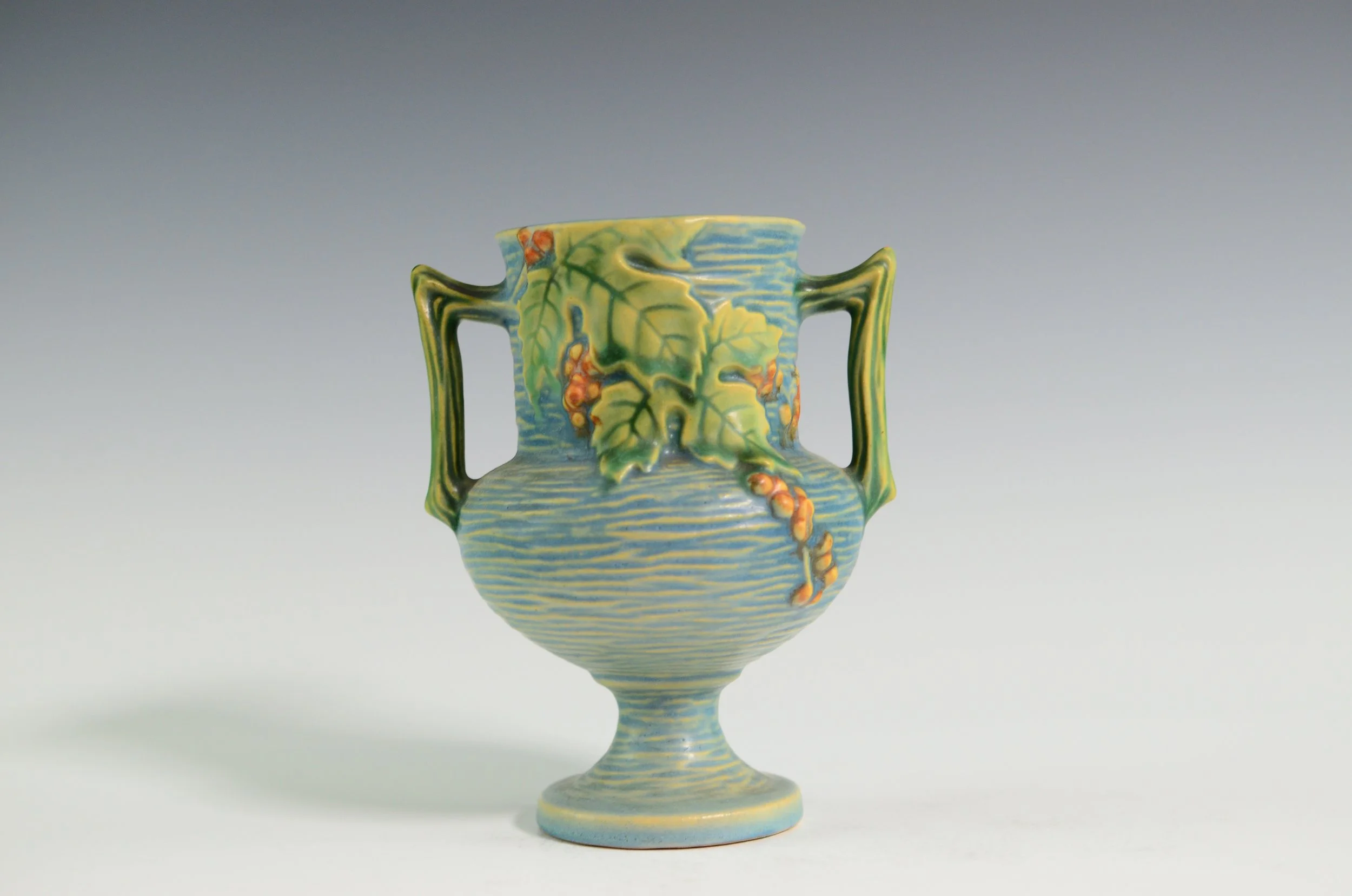 Roseville Pottery Company (1890-1954). Bushberry Vase in Blue with Leaves and Berries