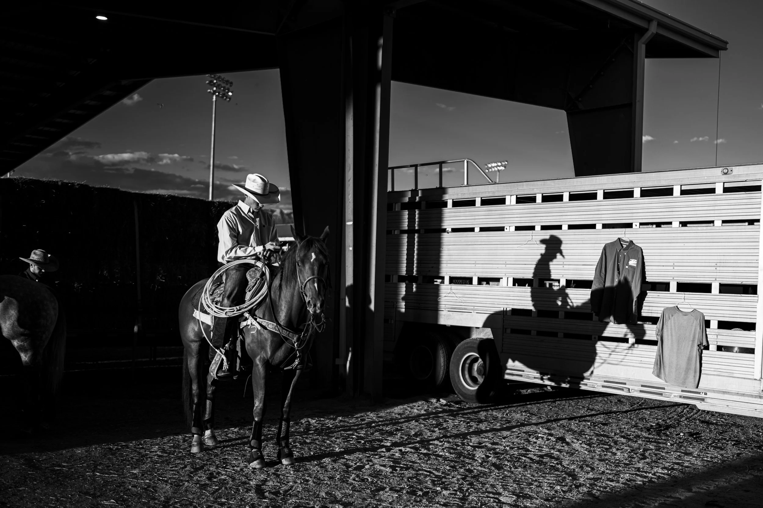 Black-and-white photograph of a cowboy on horseback beside a livestock trailer at the New Mexico State Fair Rodeo.