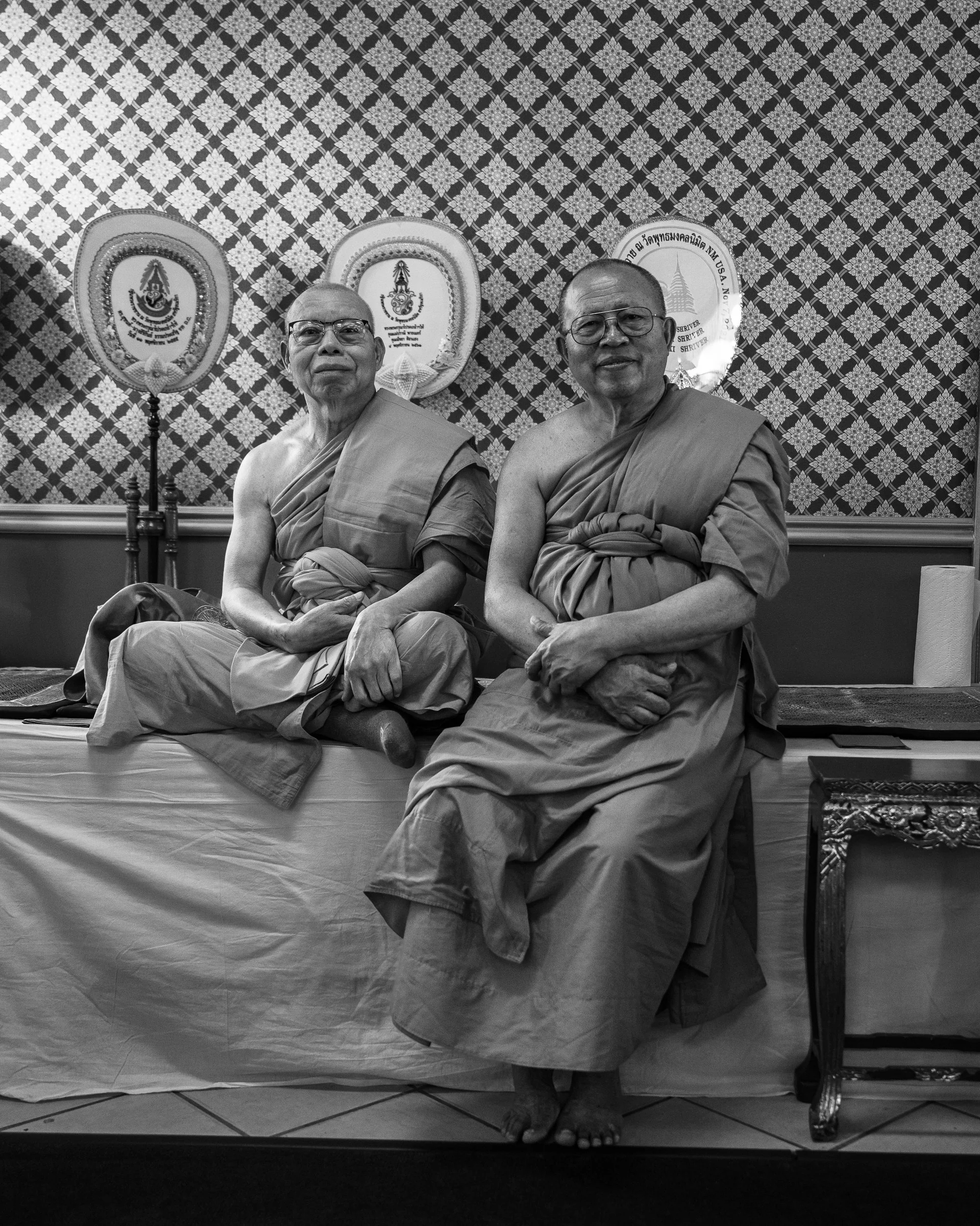 Black-and-white portrait of two Buddhist monks seated indoors in Albuquerque’s International District.