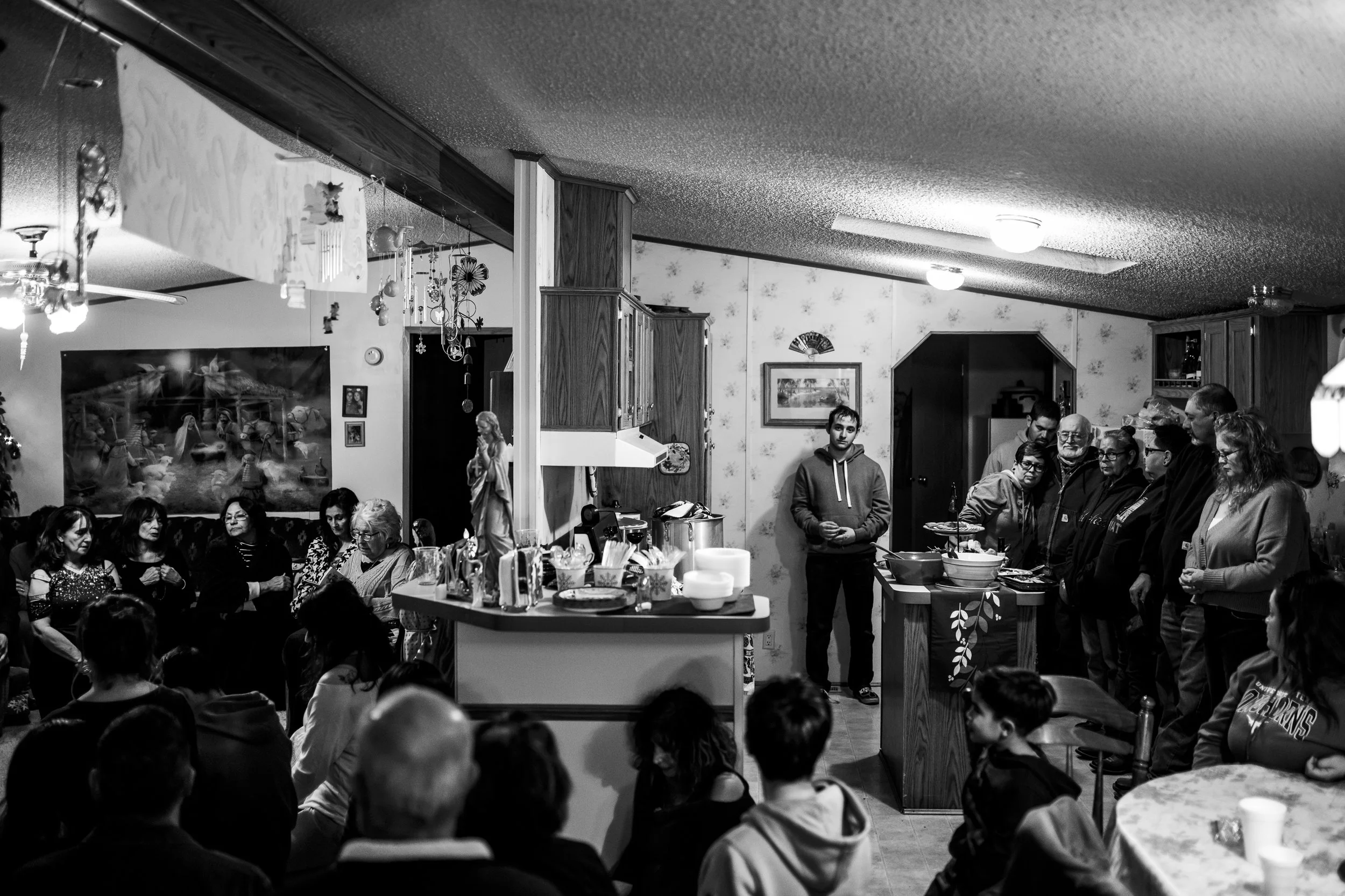 Black-and-white photograph of a family and community gathering inside a home during Las Posadas in La Jolla, New Mexico.