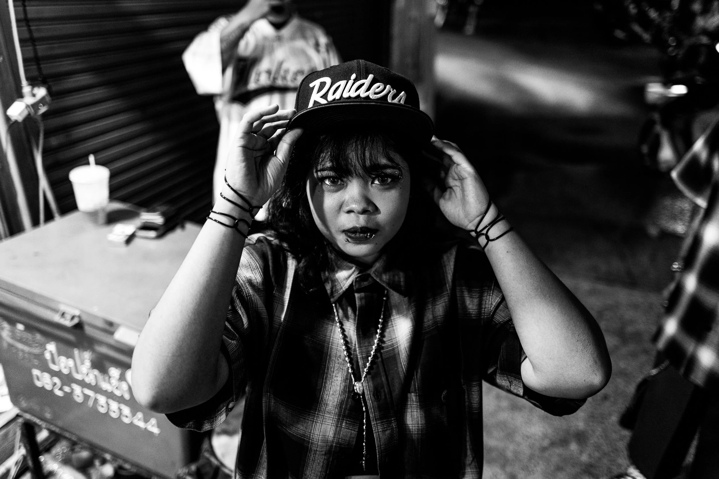 black and white photo of a woman in a Raiders hat. Bangkok Thailand. Chicano Culture 