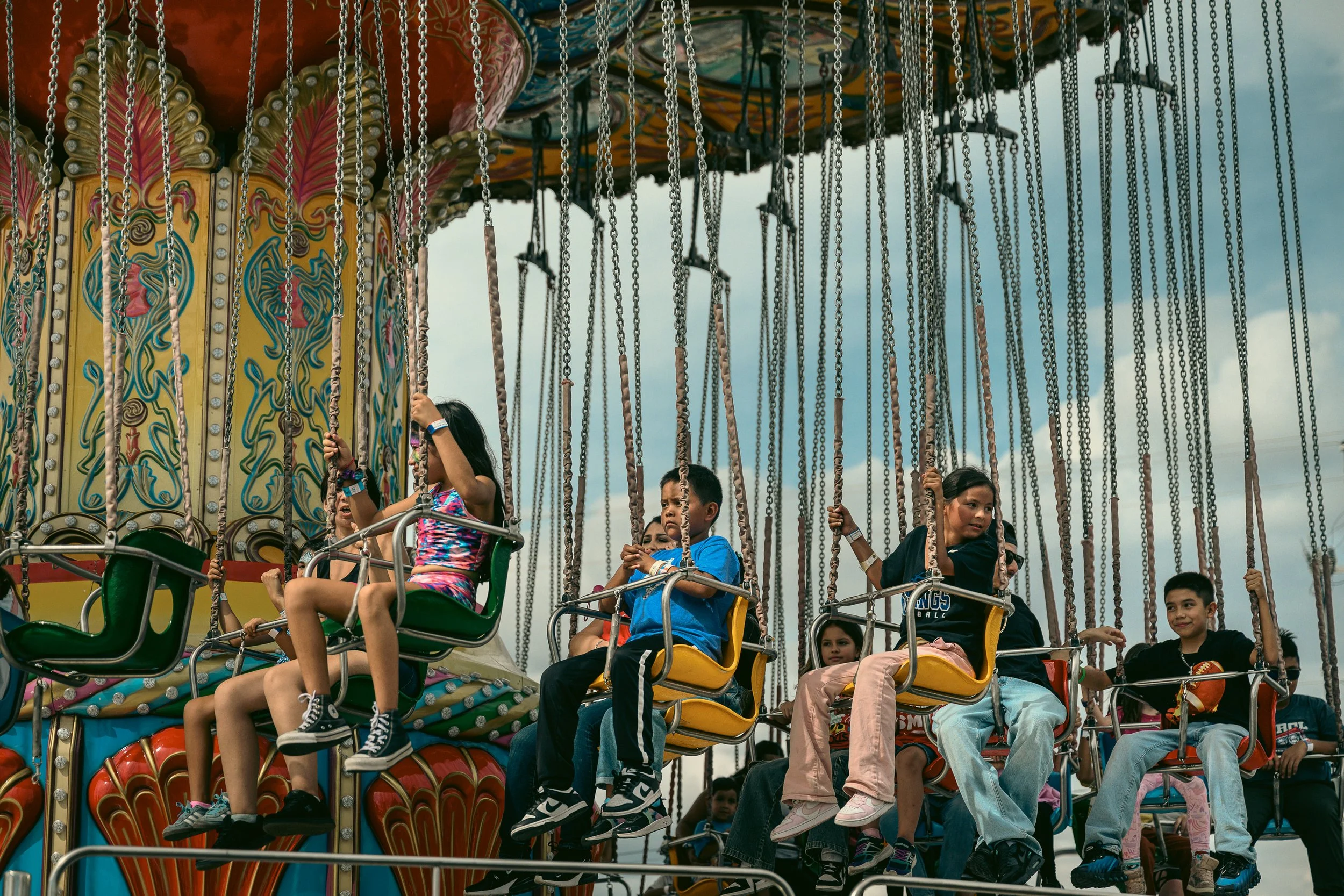 Children riding a colorful swing carousel at an amusement park.