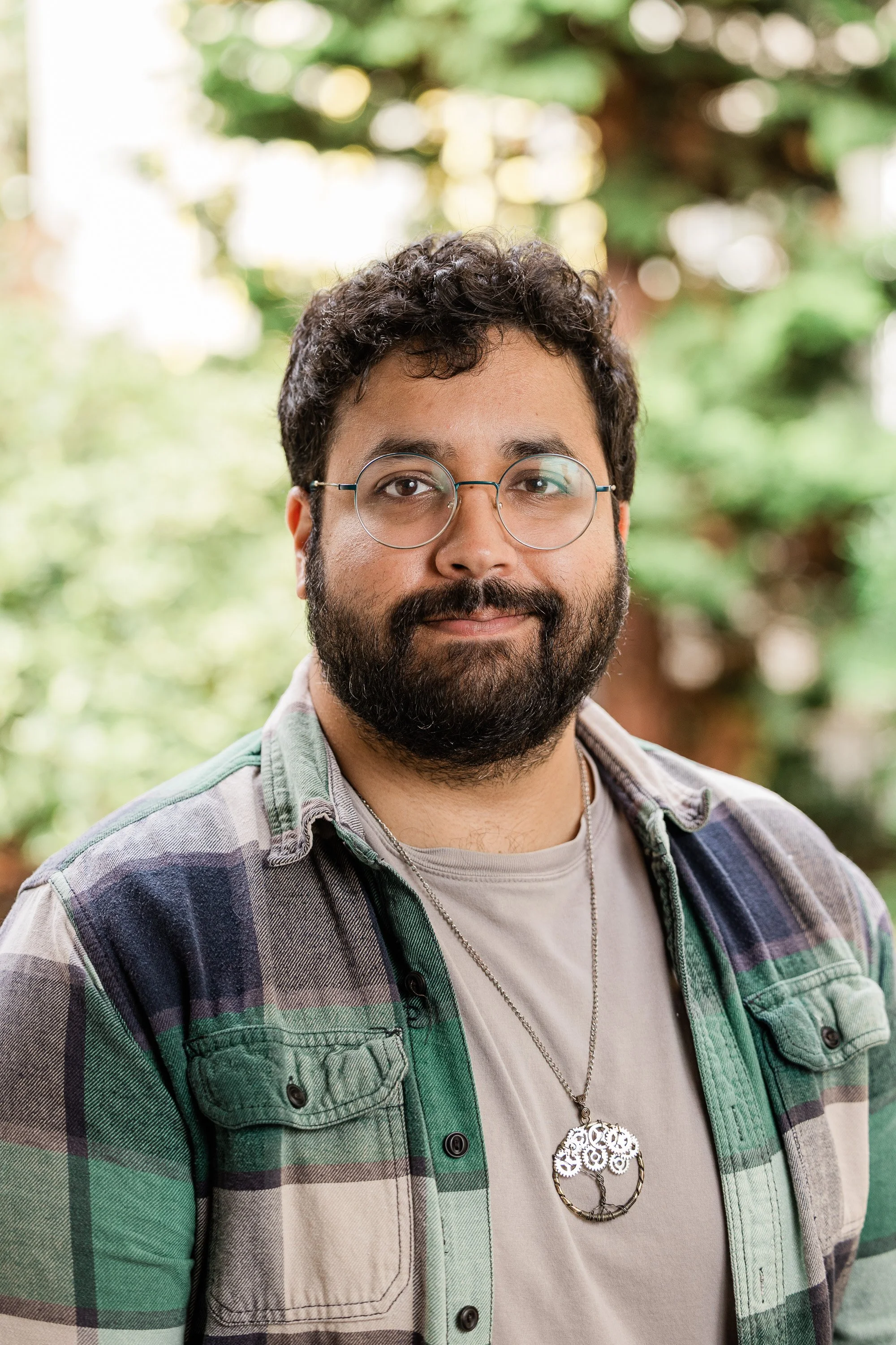 A man with glasses and a beard smiling in an outdoor setting.
