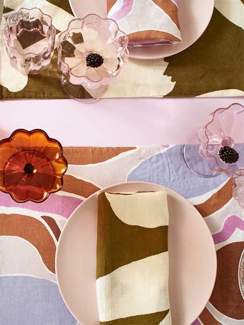 Cloth Napkins: Mosey Me's patterned brown and white napkins are set on a pink plate, on top of a matching patterned placemat.