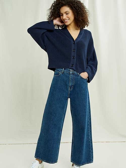 Eco-Friendly Clothing Brands: Model wears People Tree blue oversized crop cardigan with flared medium-wash jeans