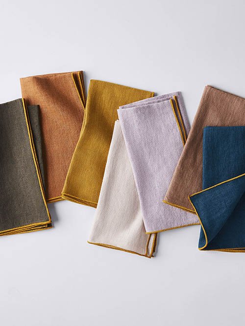 Cloth Napkins: MADRE's six-piece napkin set lays out with varying colors including rust orange, terracotta yellow, and lavender.