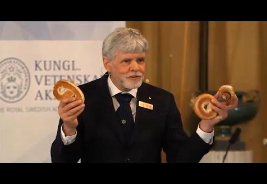 Figure 3. Thors Hans Hansson of the Nobel Committee explains the intuition and importance of the honored discoveries using pastries.