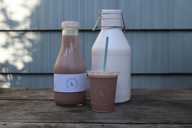 Cups and growlers of Bellflower Chocolate Company's botanical, bean-to-bottle™ chocolate milk.&nbsp;
