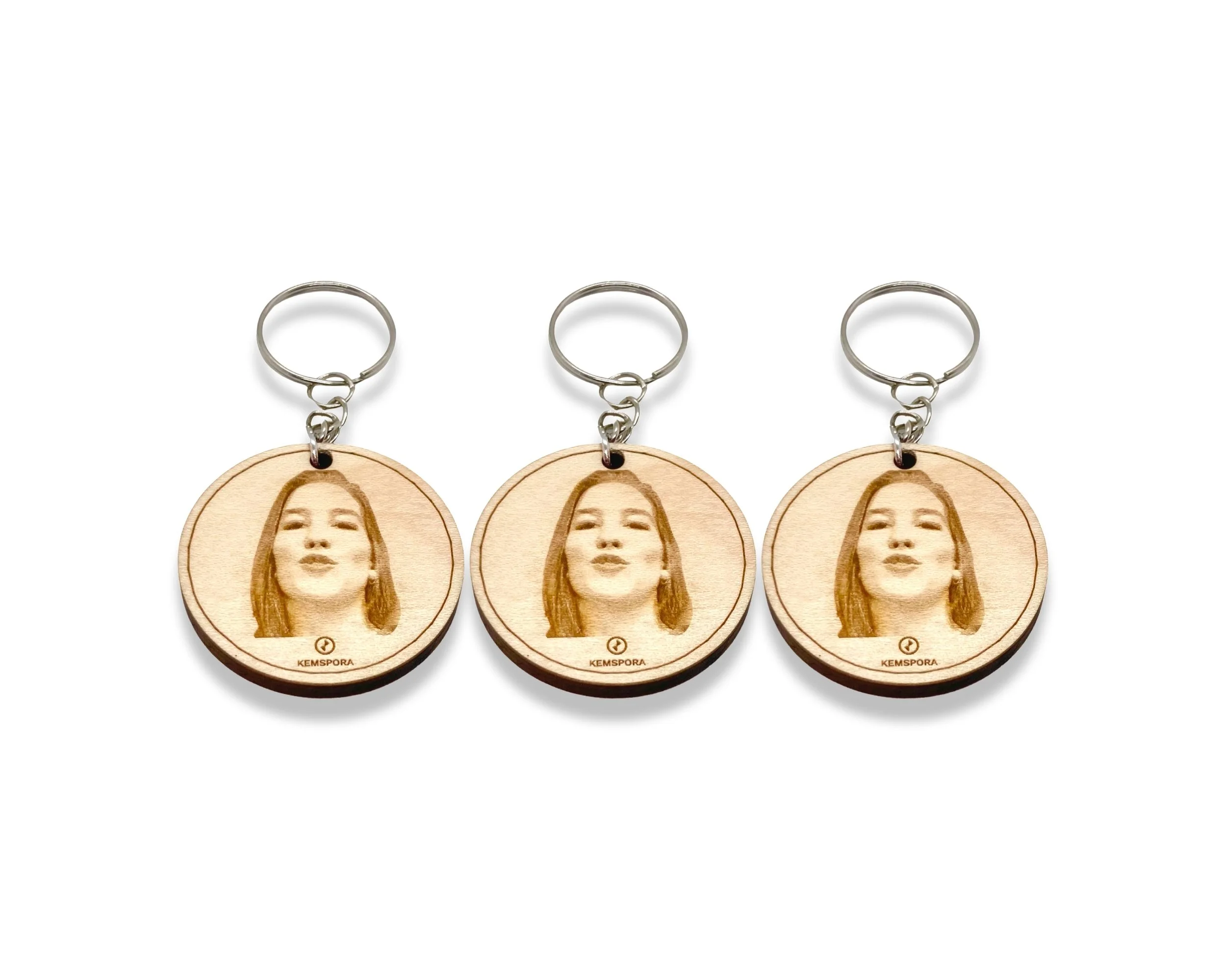 A set of 3 Kemspora custom art laser engraving, on a uniquely stylish circular, wooden, Keyring, of a woman with long smiling.