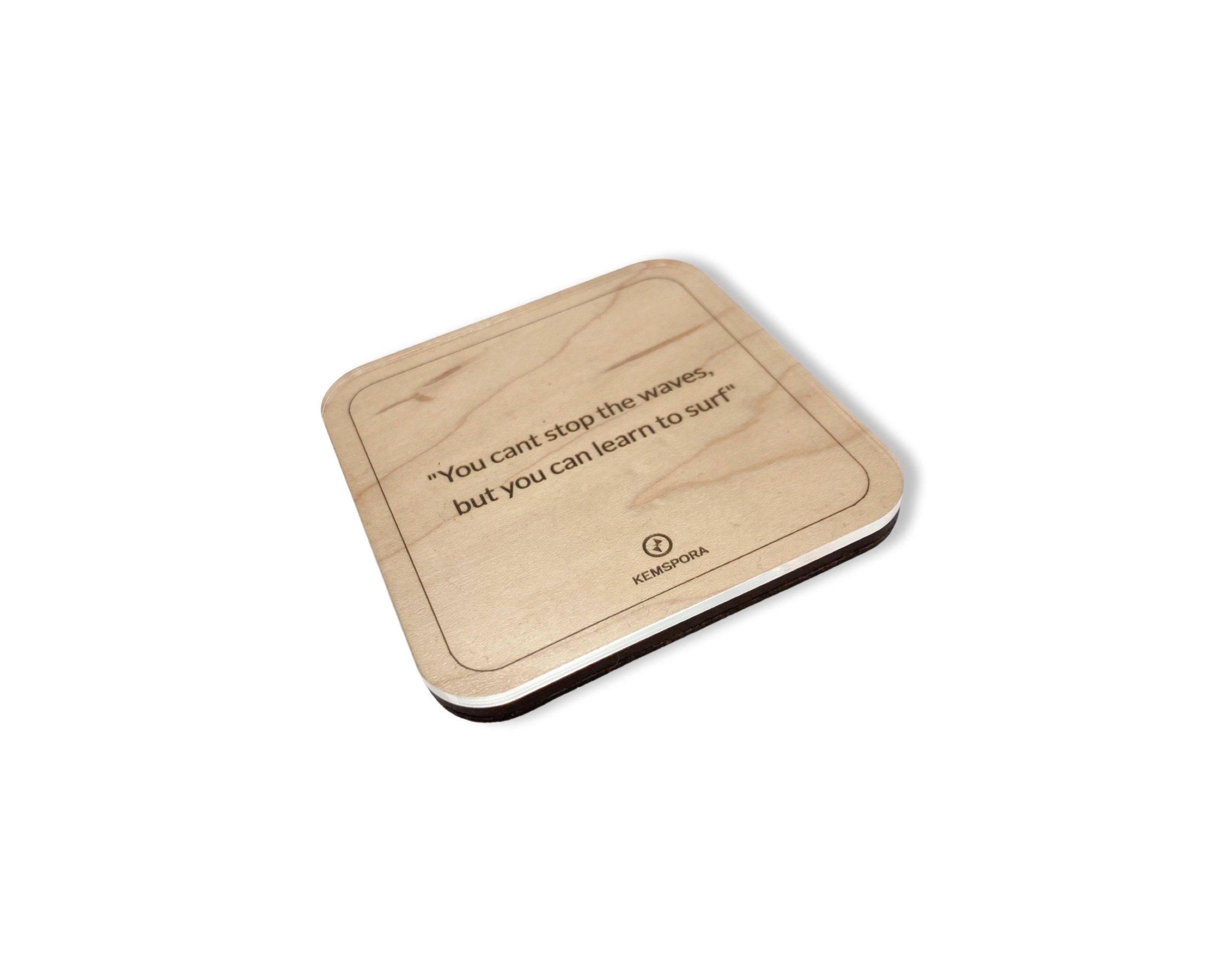 A Kemspora custom art laser engraving, on a uniquely stylish square wooden coaster, with text reading, You can't stop the waves but you can learn how to surf. Coaster has a clear acrylic covering.