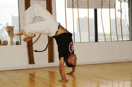 A Capoeira practitioner balances upside down during training.