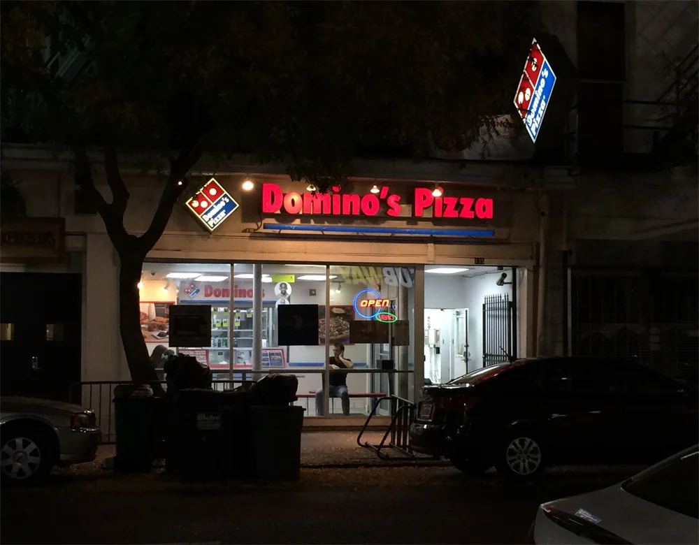 A performer sits in the window of Domino's storefront