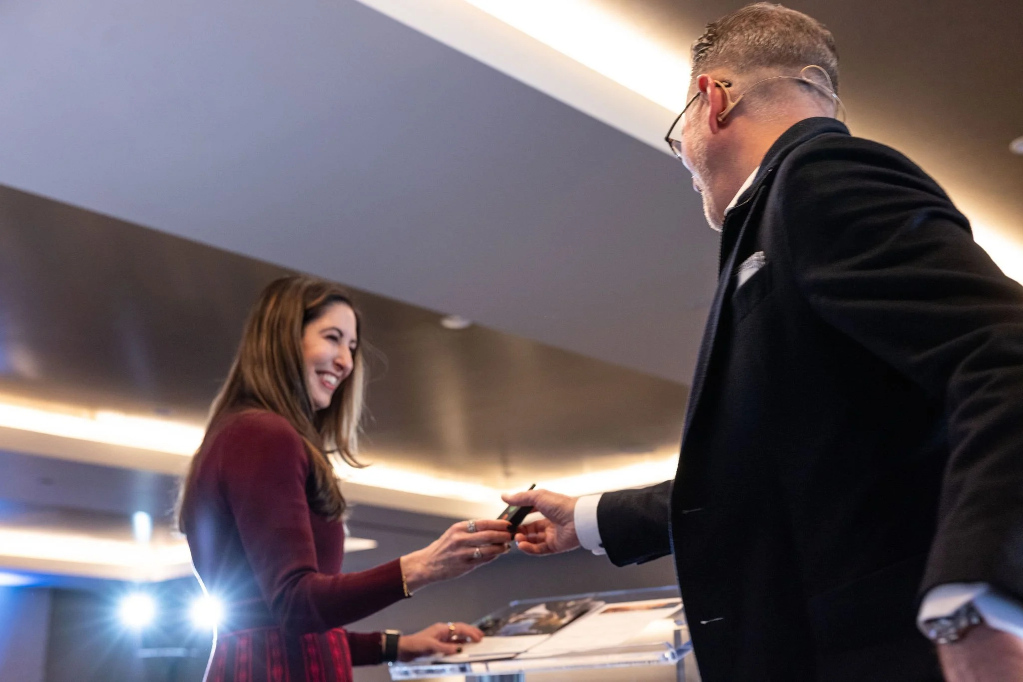 Smiling attendee greeting an executive with a handshake at a corporate conference